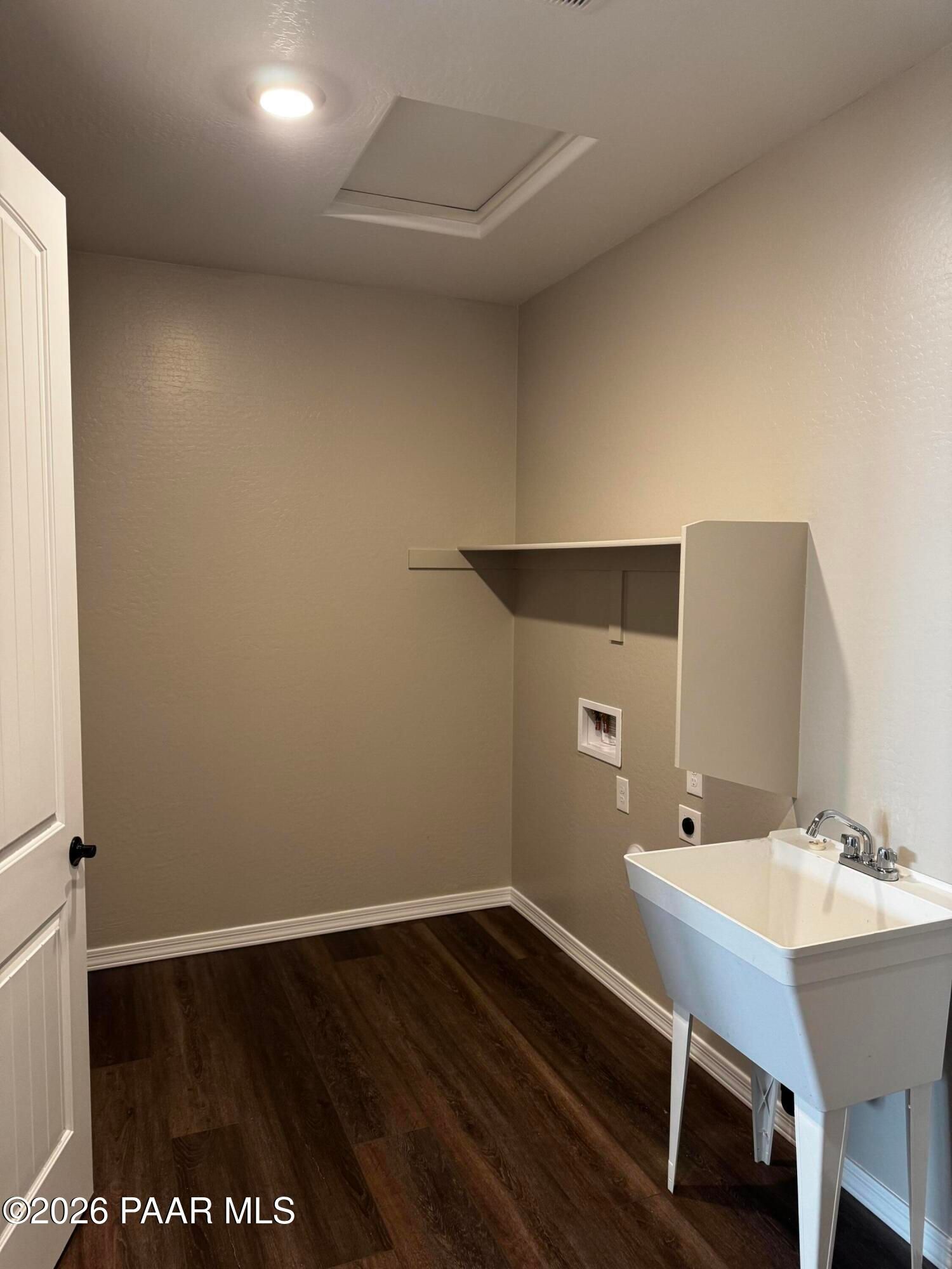 Bright laundry room with utility sink, washer/dryer hookups, built-in shelving, and hardwood floors in Davidson Homes The Durango II B, Prescott AZ