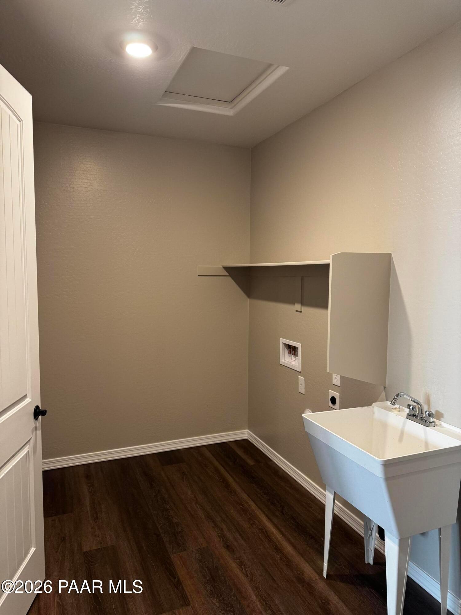 Bright laundry room with utility sink, washer/dryer hookups, built-in shelving, and hardwood floors in Davidson Homes The Durango II B, Prescott AZ