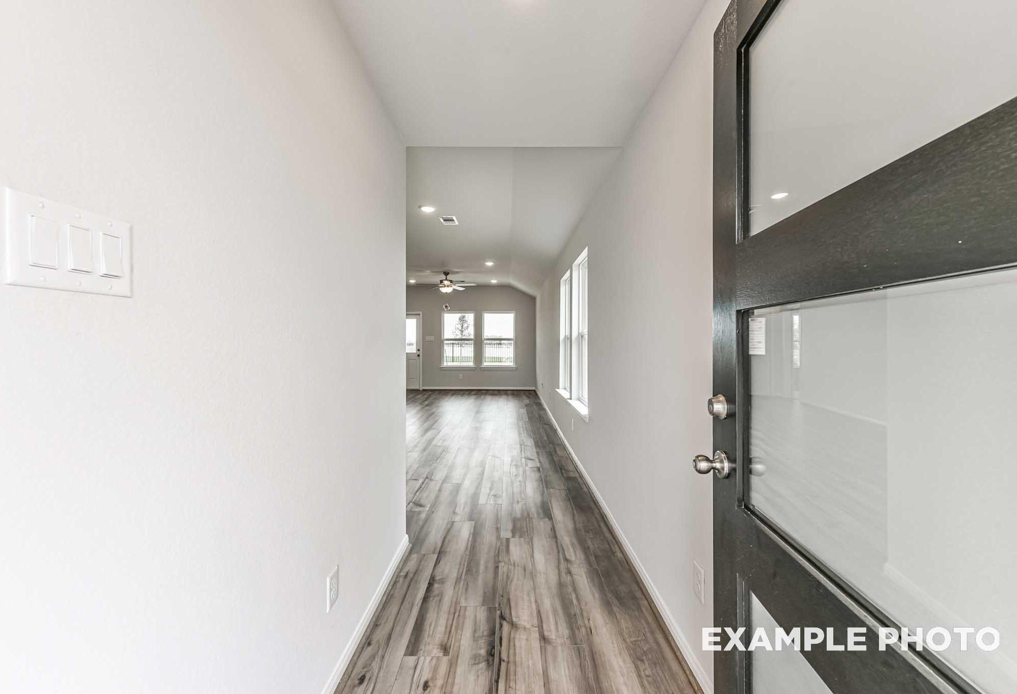 Spacious entry hallway in The Costa A home featuring hardwood floors, white walls, and frosted glass door