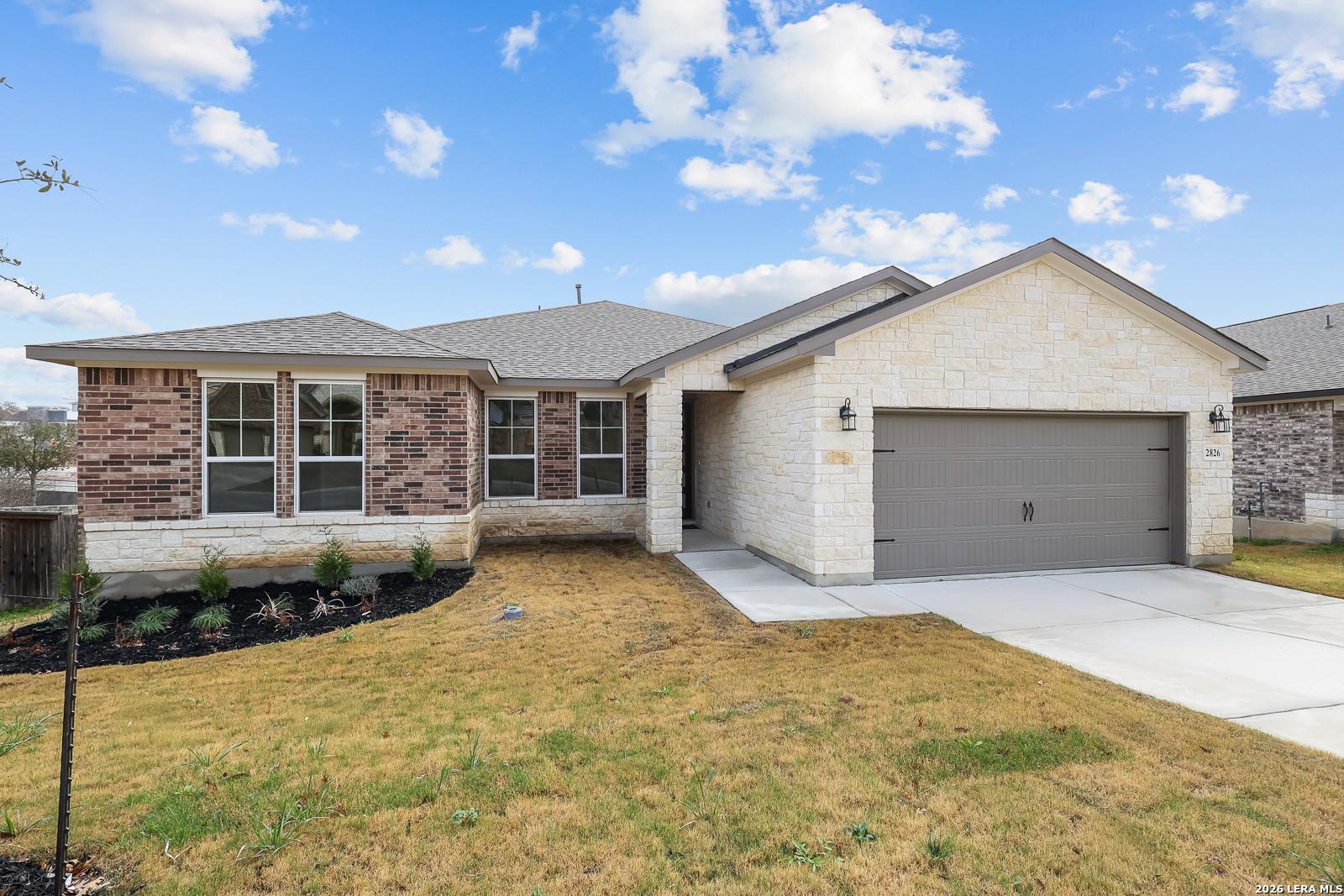 Modern 1-story Rockford G home with brick and stone facade, 2-car garage, and landscaped yard in Ladera, San Antonio, Texas