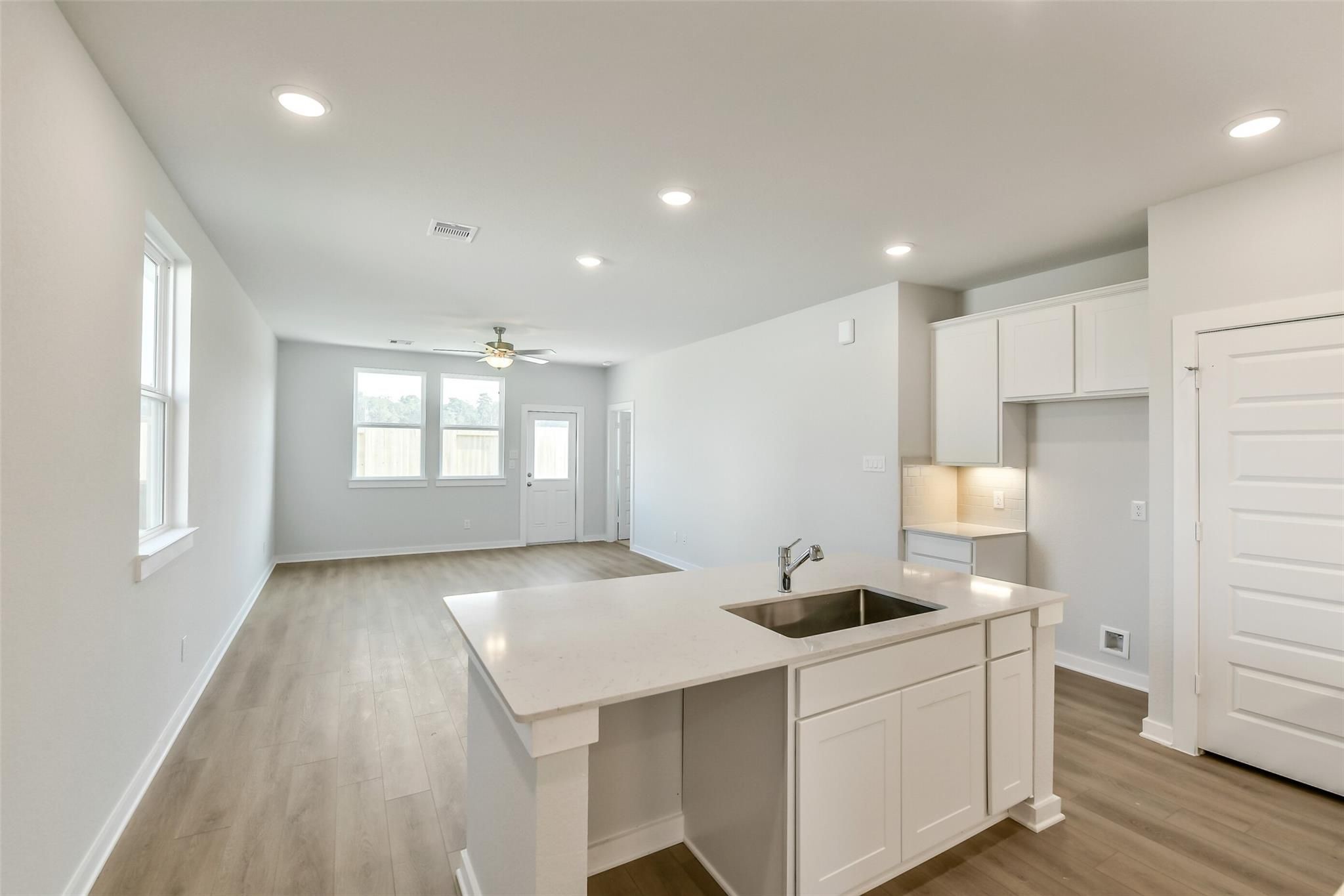 Open-concept kitchen with white quartz island, sink, and cabinets in Davidson Homes Colorado F 4-bedroom, Cleveland, Texas