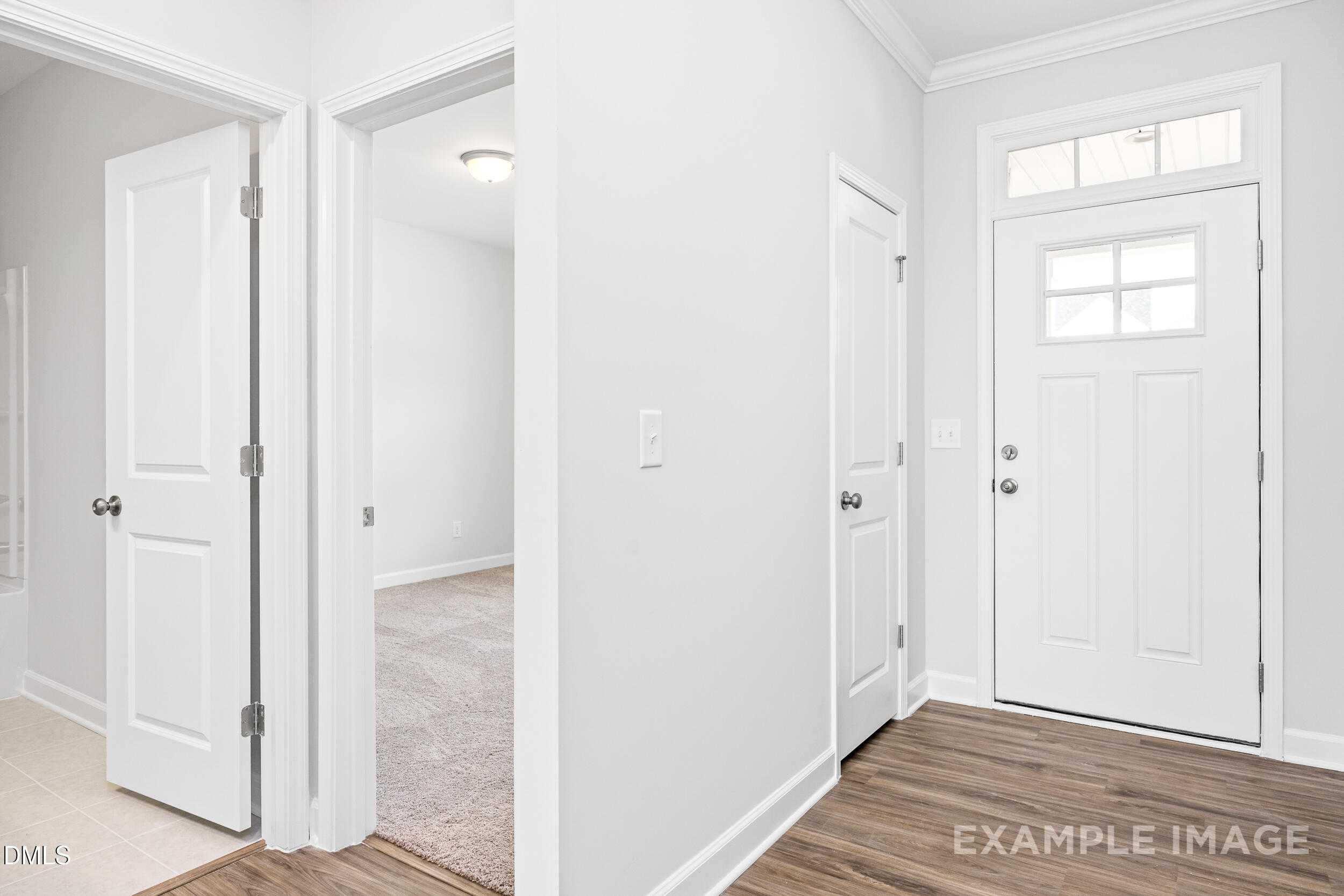 Welcoming entryway with glass-paneled white front door, adjacent bedroom, hardwood floors in Davidson Homes The Franklin C, Lillington, NC