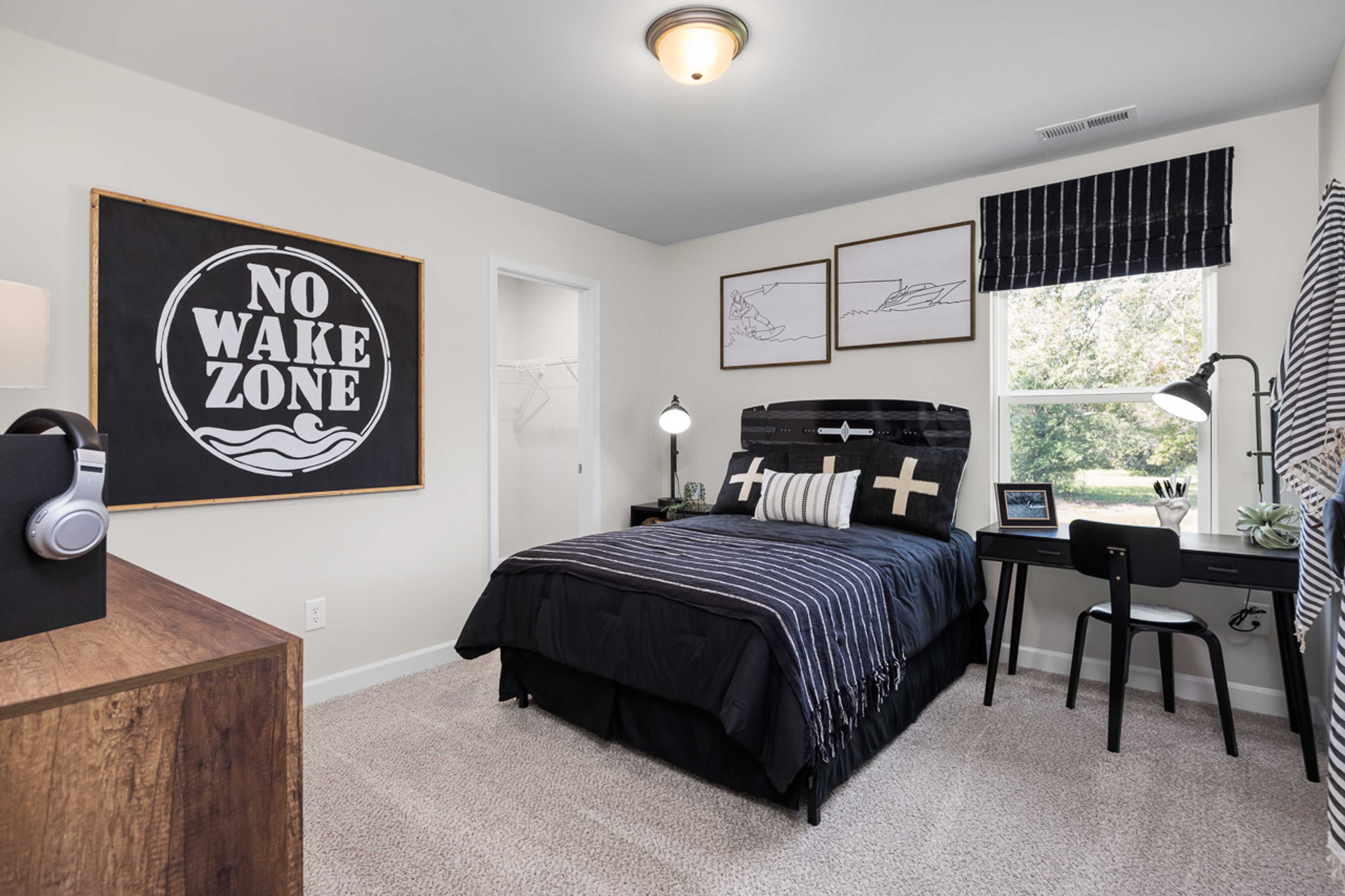 Contemporary teen bedroom at Wellers Knoll in Lillington NC with navy bedding, wooden desk, and No Wake Zone wall sign