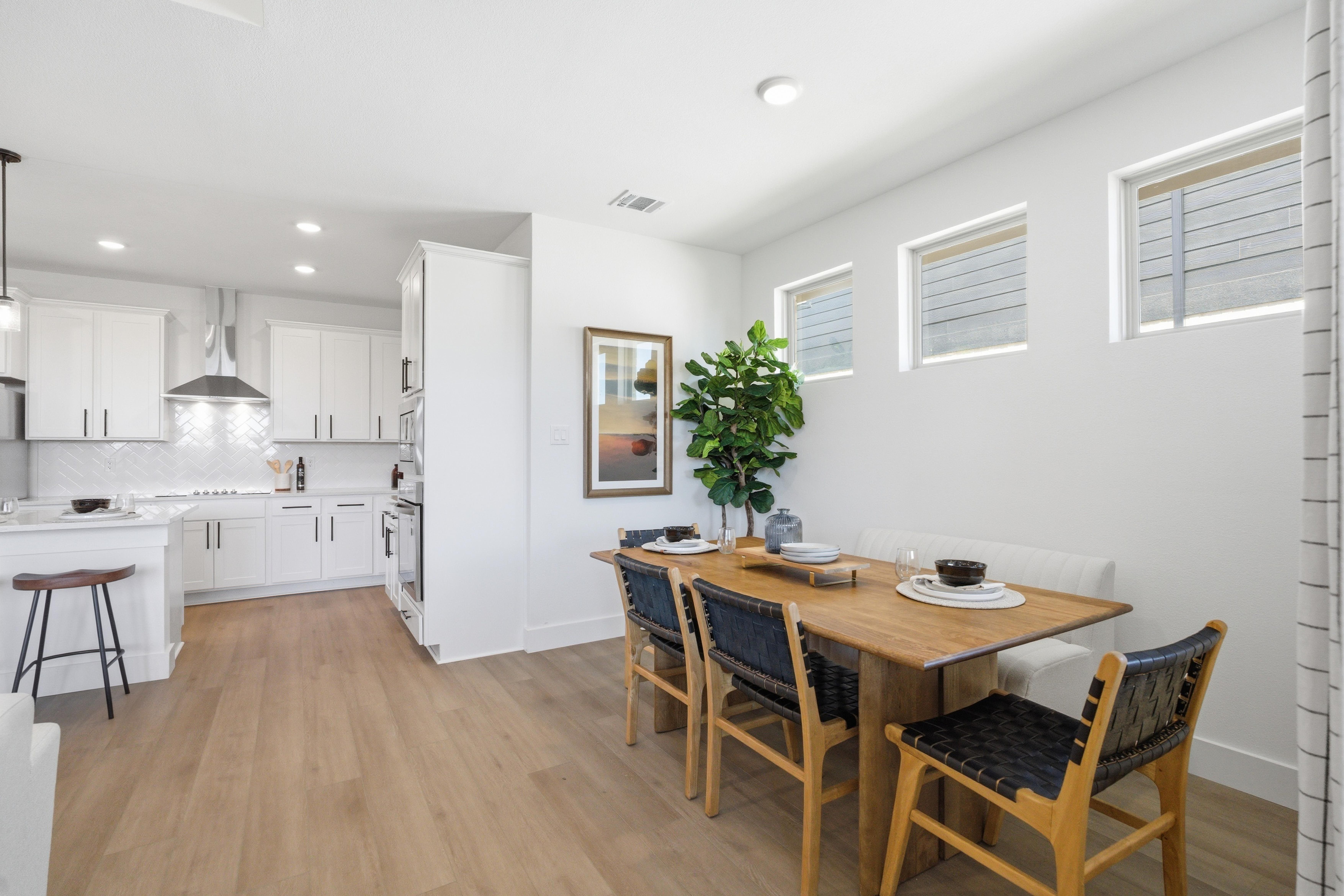 Open-concept kitchen and dining area at Mercer Meadows in Royse City TX with white cabinets, wooden table, and hardwood floors