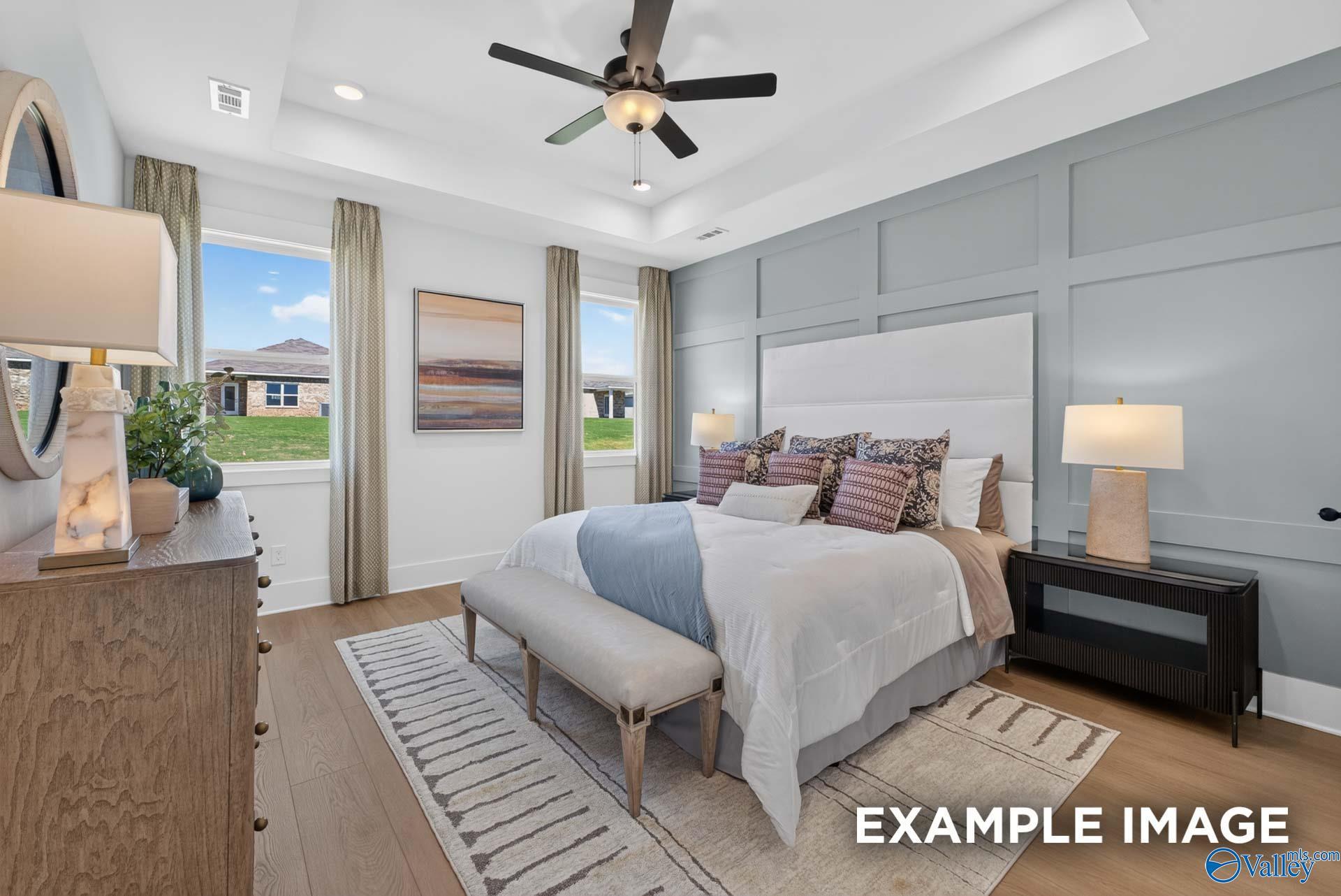Primary bedroom with tray ceiling, accent wall, and ceiling fan in The Ashport K floor plan at Forest Glen, Hazel Green, Alabama