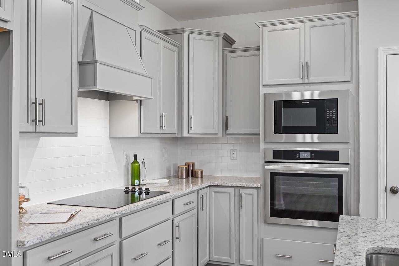 Modern gray shaker cabinets, quartz countertops, stainless Frigidaire double oven, subway tile backsplash in The Daphne D kitchen, Lillington NC