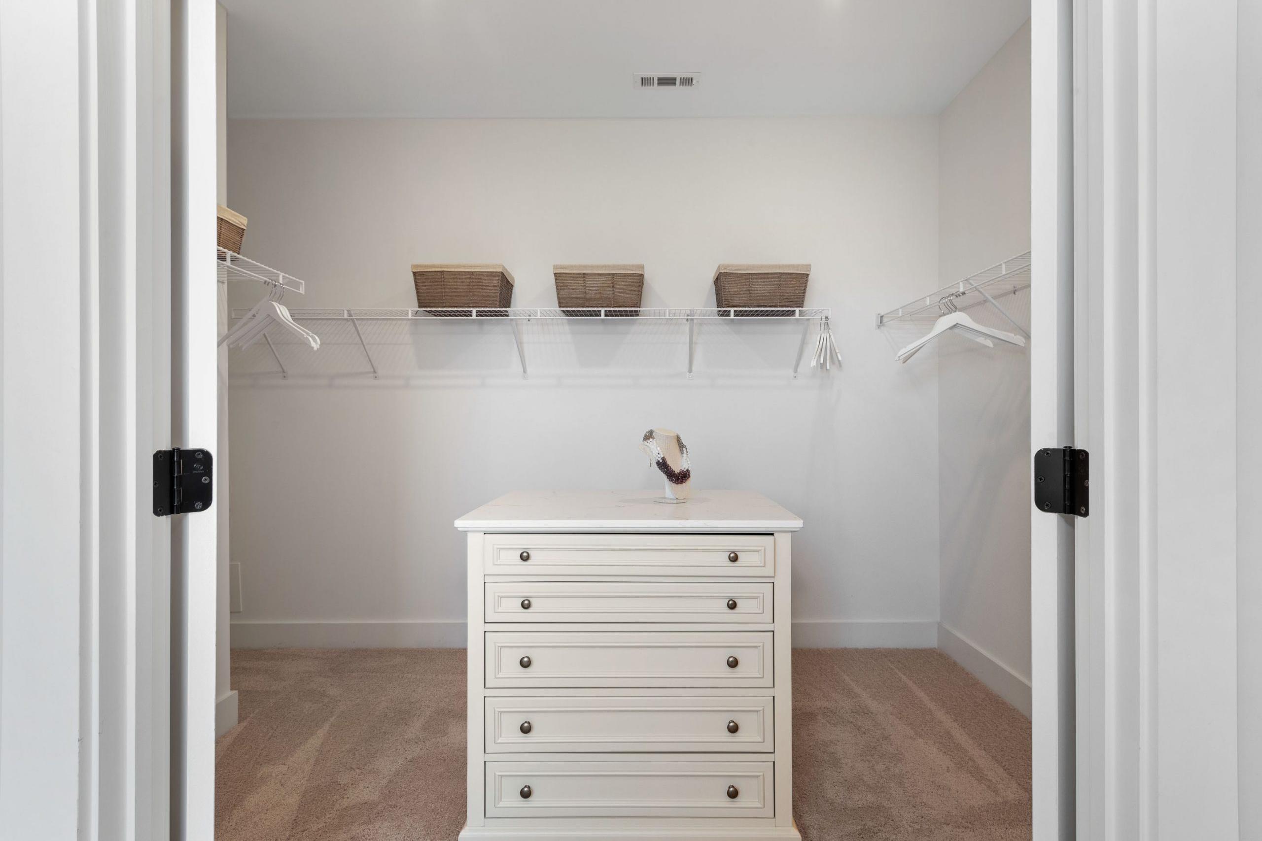Spacious walk-in closet at Rivers Edge in Murfreesboro TN by Davidson Homes with white dresser shelving and hanging rods