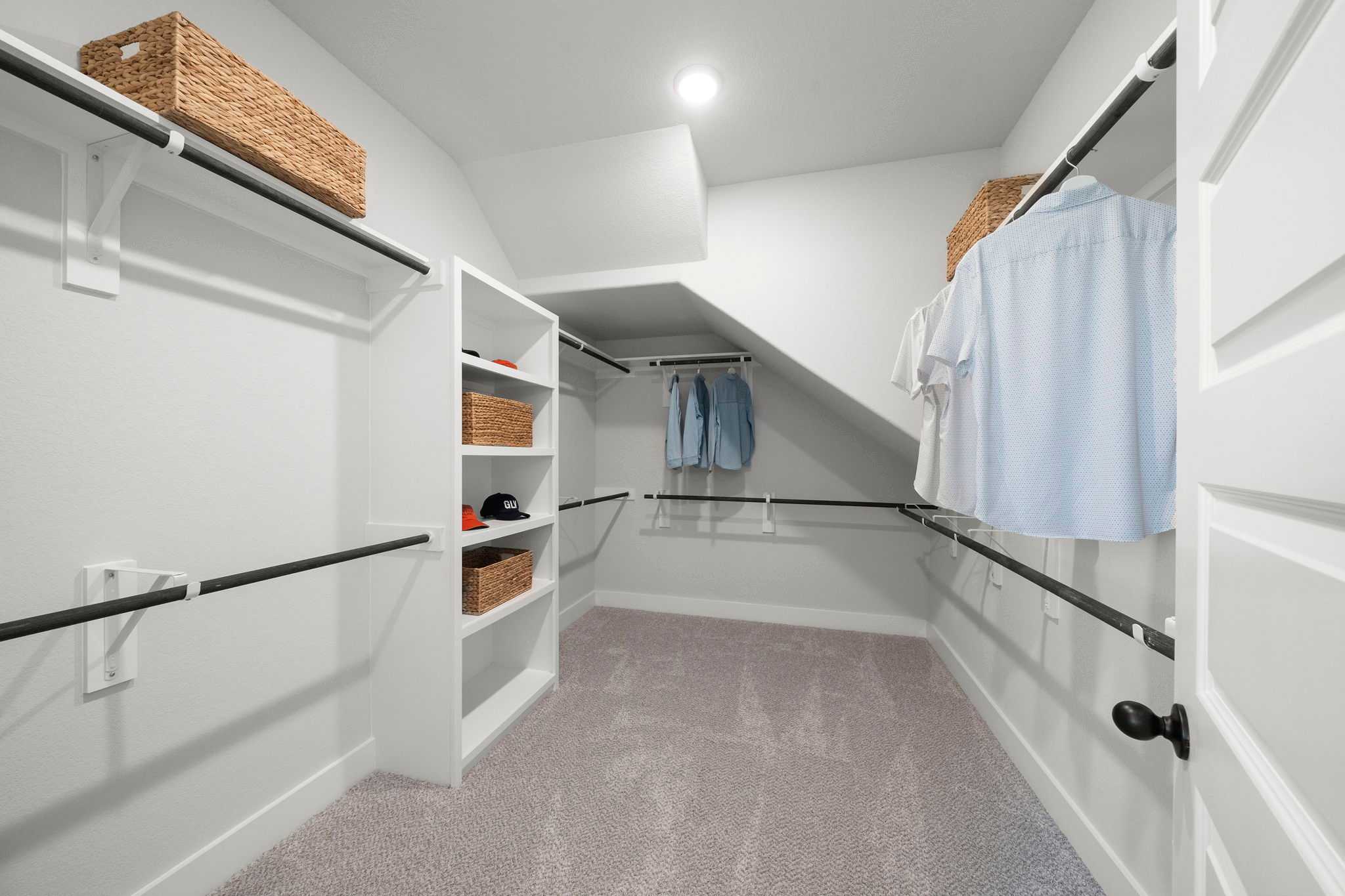 Spacious walk-in closet at Lago Mar in Texas City, Texas by Davidson Homes with white shelving, hanging rods and woven baskets