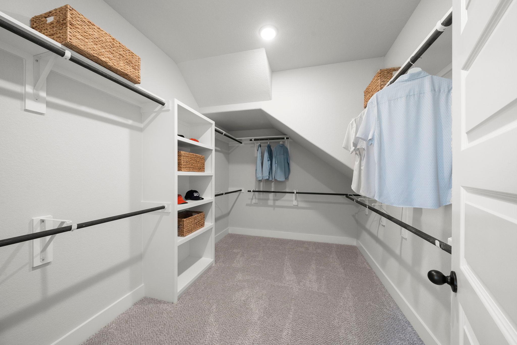 Spacious walk-in closet at Lago Mar in Texas City, Texas by Davidson Homes with white shelving, hanging rods and woven baskets