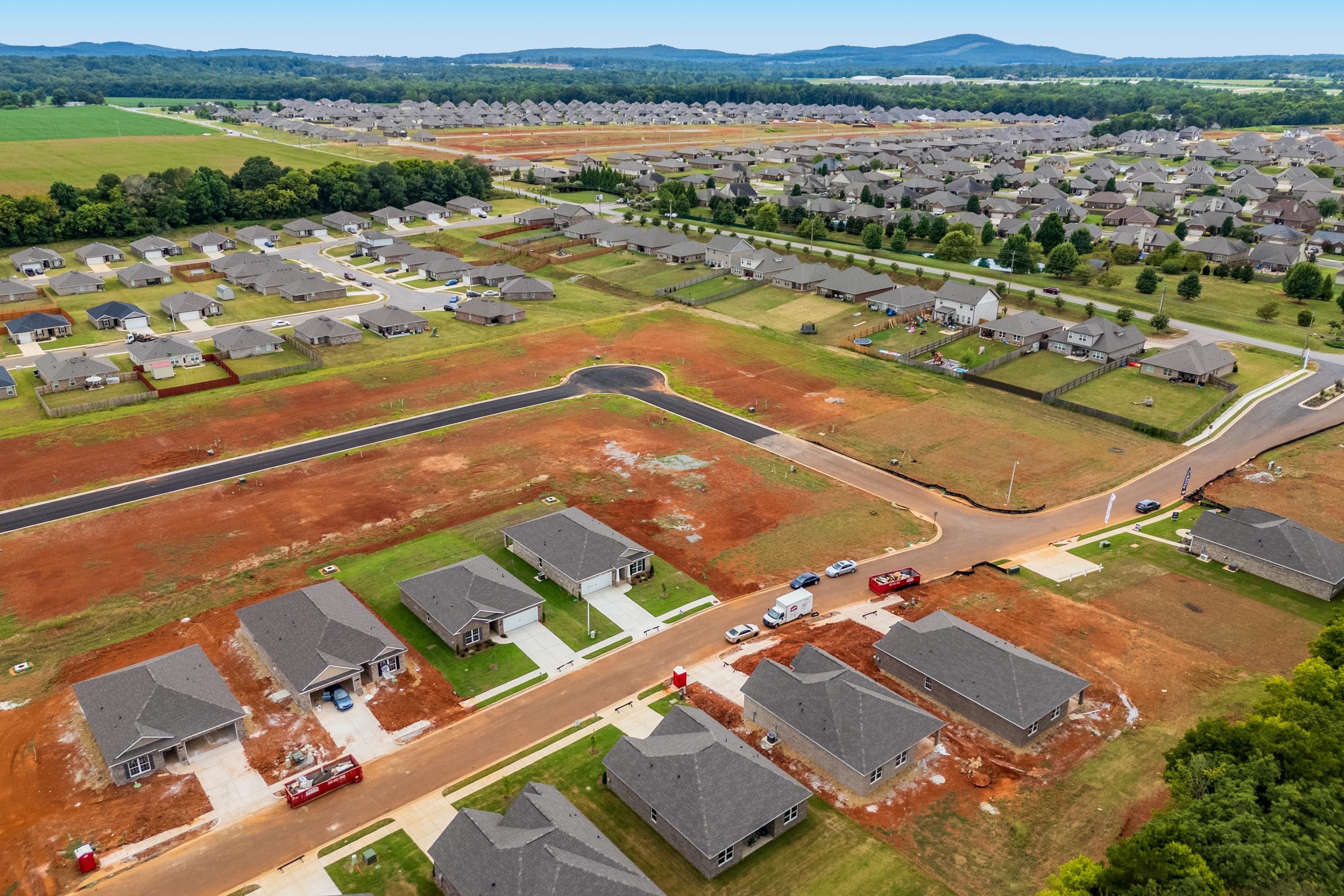 Aerial view of Lynn Meadows neighborhood in Meridianville Alabama with new Davidson Homes gray roofs red dirt roads and construction