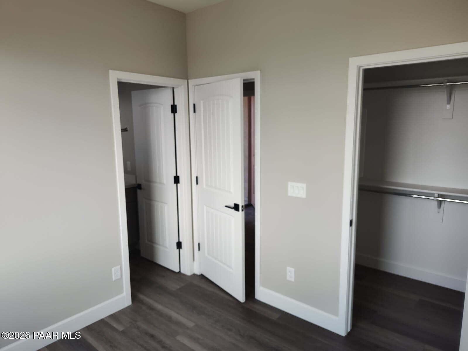 Master bedroom with en-suite bath and walk-in closet, beige walls, gray luxury vinyl plank flooring in Davidson Homes The Harmony C, Prescott Valley, AZ