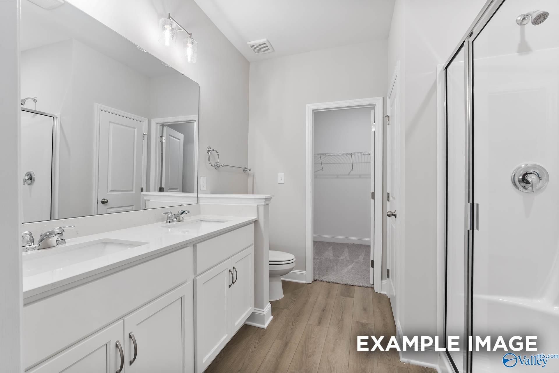 Modern master bathroom with double vanity, frameless shower, and linen closet in Davidson Homes The Asheville C, Huntsville, AL