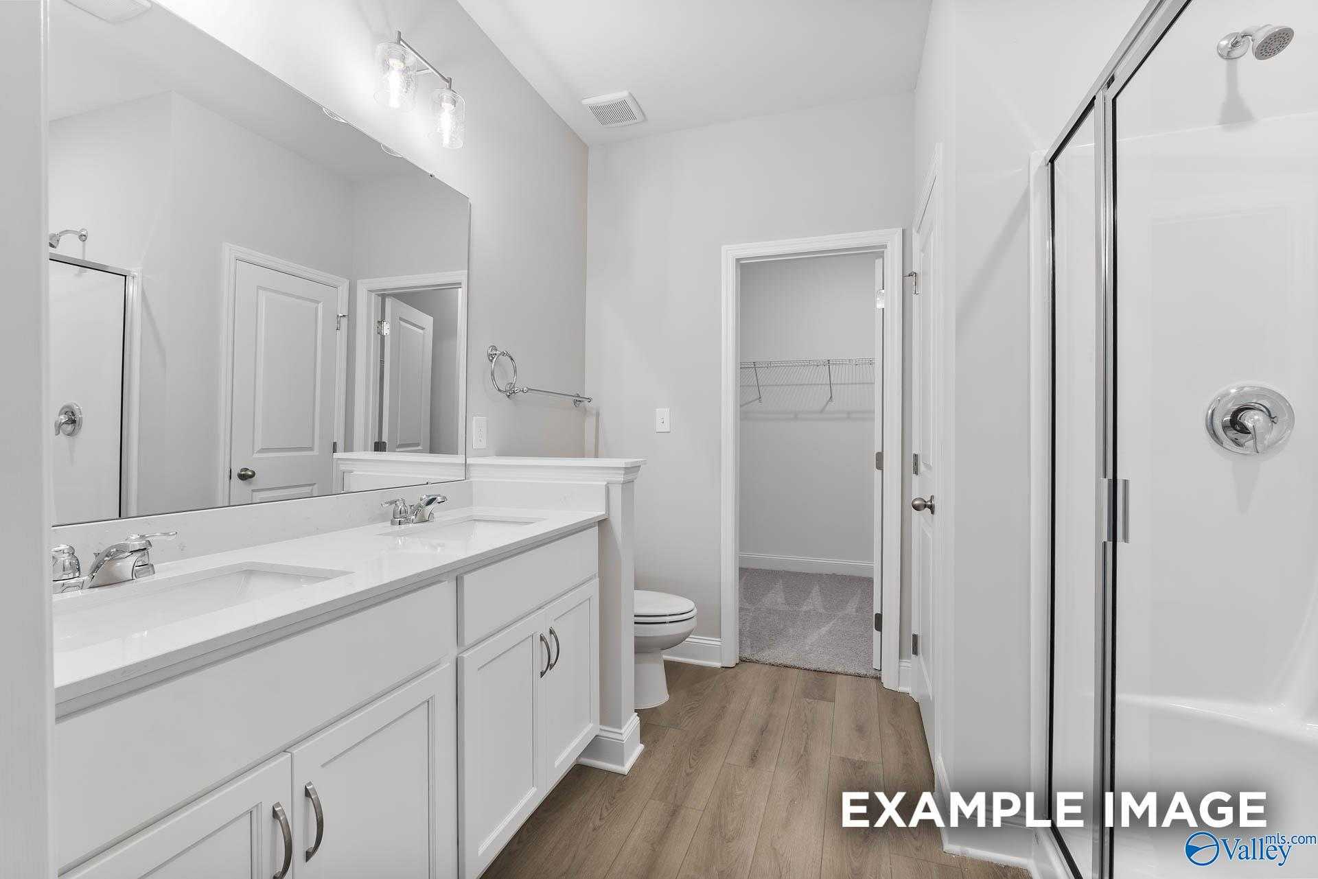 Modern master bathroom with double white vanity, frameless glass shower, and linen closet in Davidson Homes The Asheville C, Huntsville AL