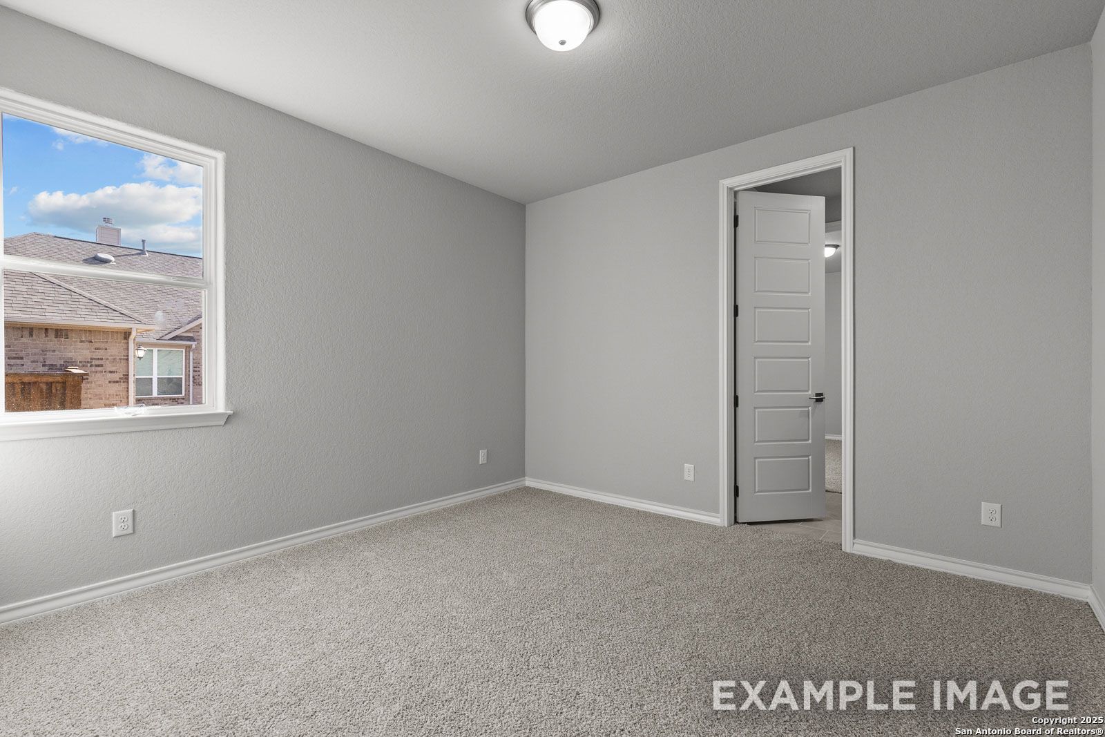 Spacious secondary bedroom in The Oxford H home design featuring neutral gray walls and plush carpeting.