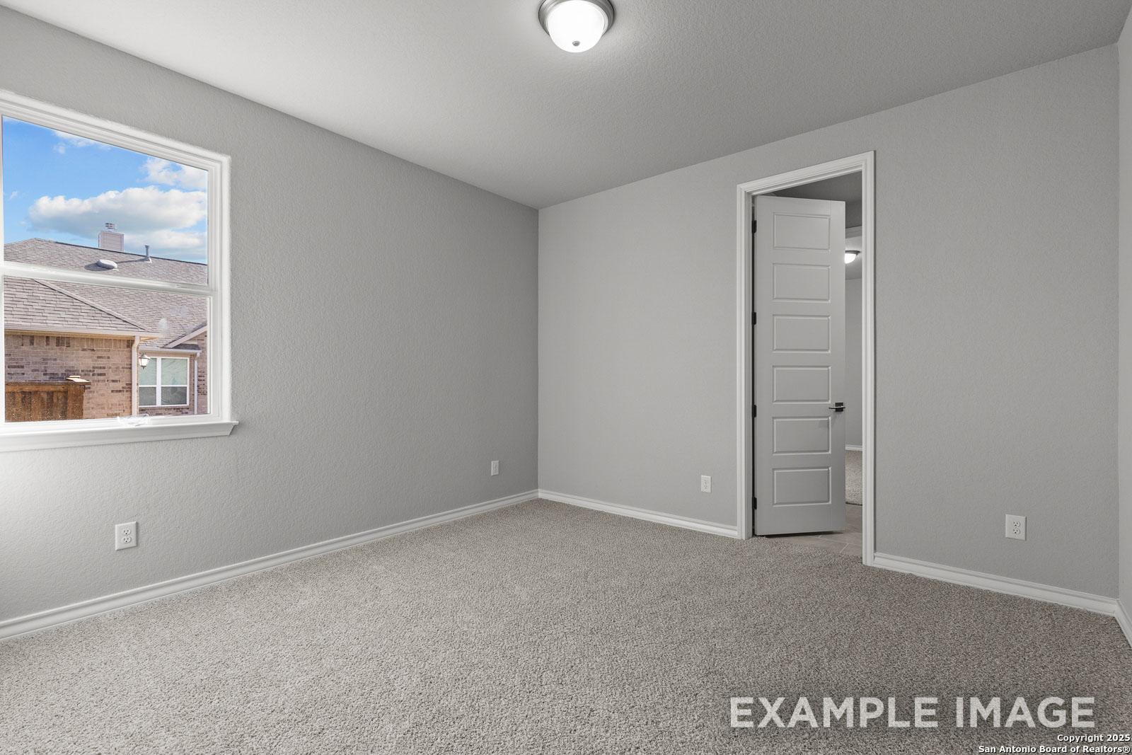 Spacious secondary bedroom in The Oxford H home design featuring neutral gray walls and plush carpeting.