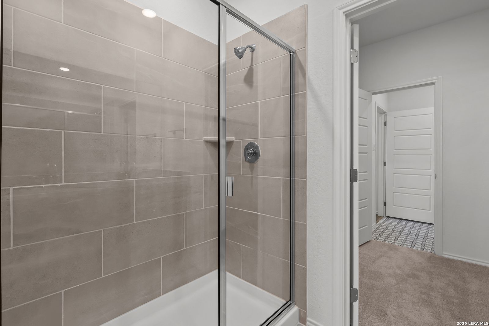 Modern walk-in glass shower with neutral tile surround in The Brazos B floor plan by Davidson Homes in Agave, San Antonio.