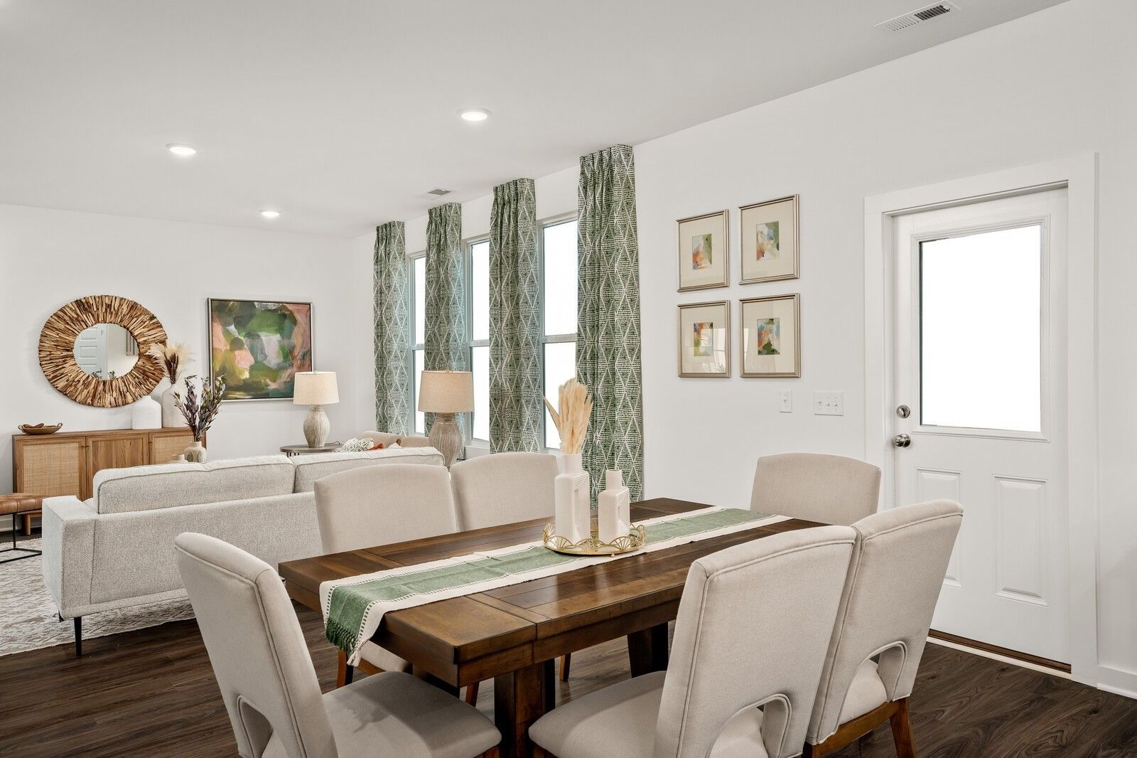 Elegant dining area with wooden table, beige chairs, sectional sofa, and large windows in Davidson Homes The Gordon C, White House, TN