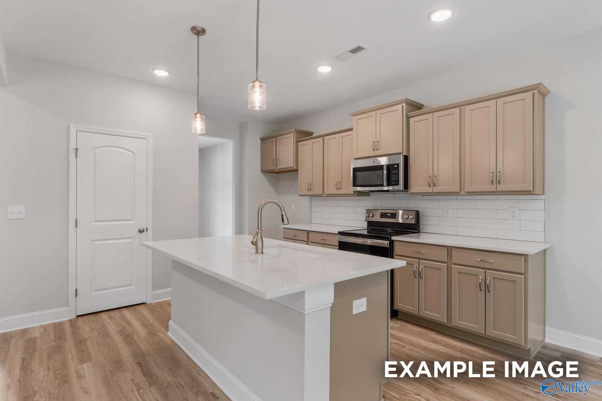 Bright kitchen with light oak cabinets, white quartz island, stainless appliances, subway tile backsplash in Davidson Homes Shelby C, Meridianville AL