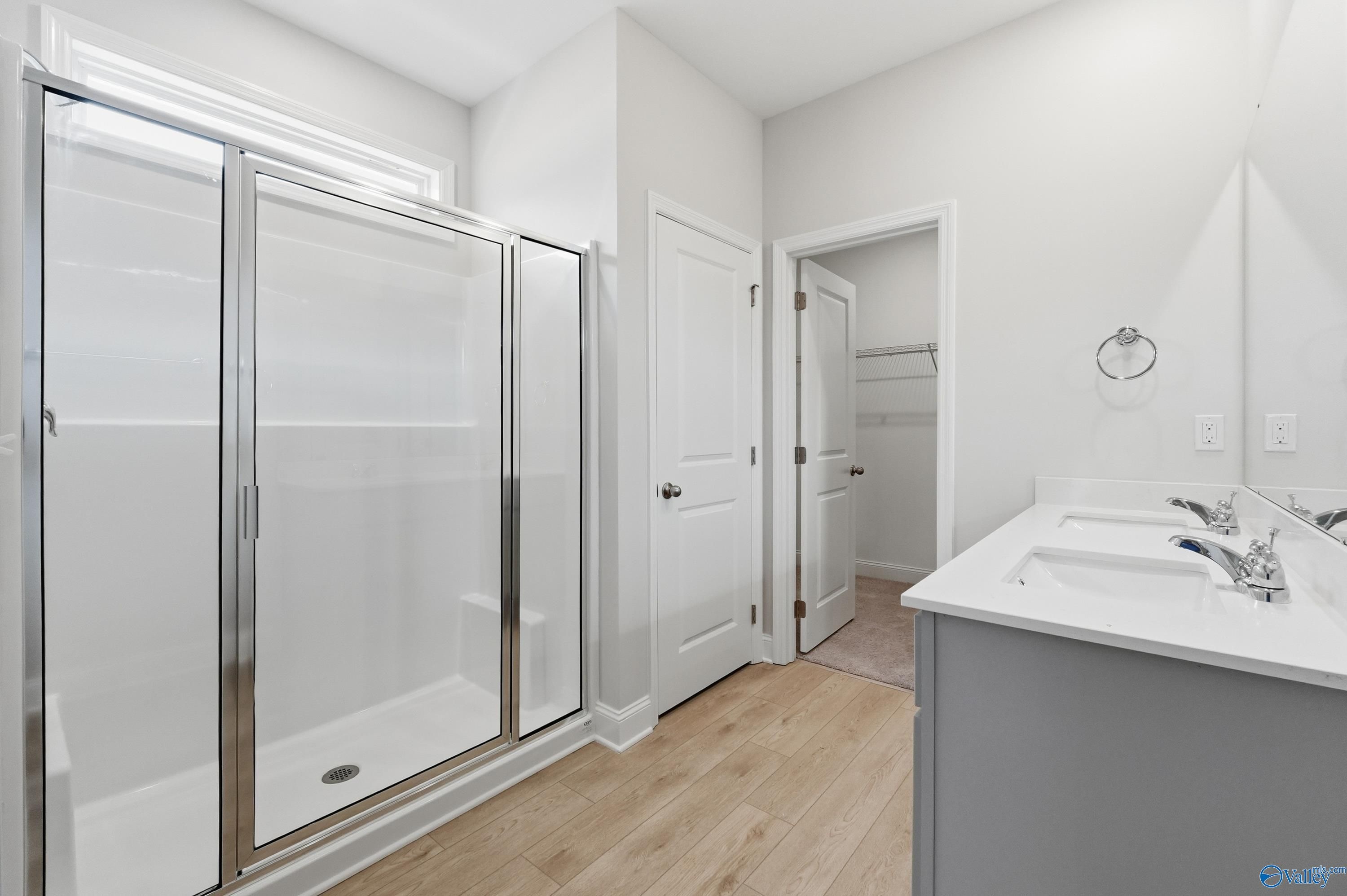 Modern master bathroom with glass-enclosed shower, double vanity, and hardwood floors in Davidson Homes The Franklin, Meridianville, Alabama