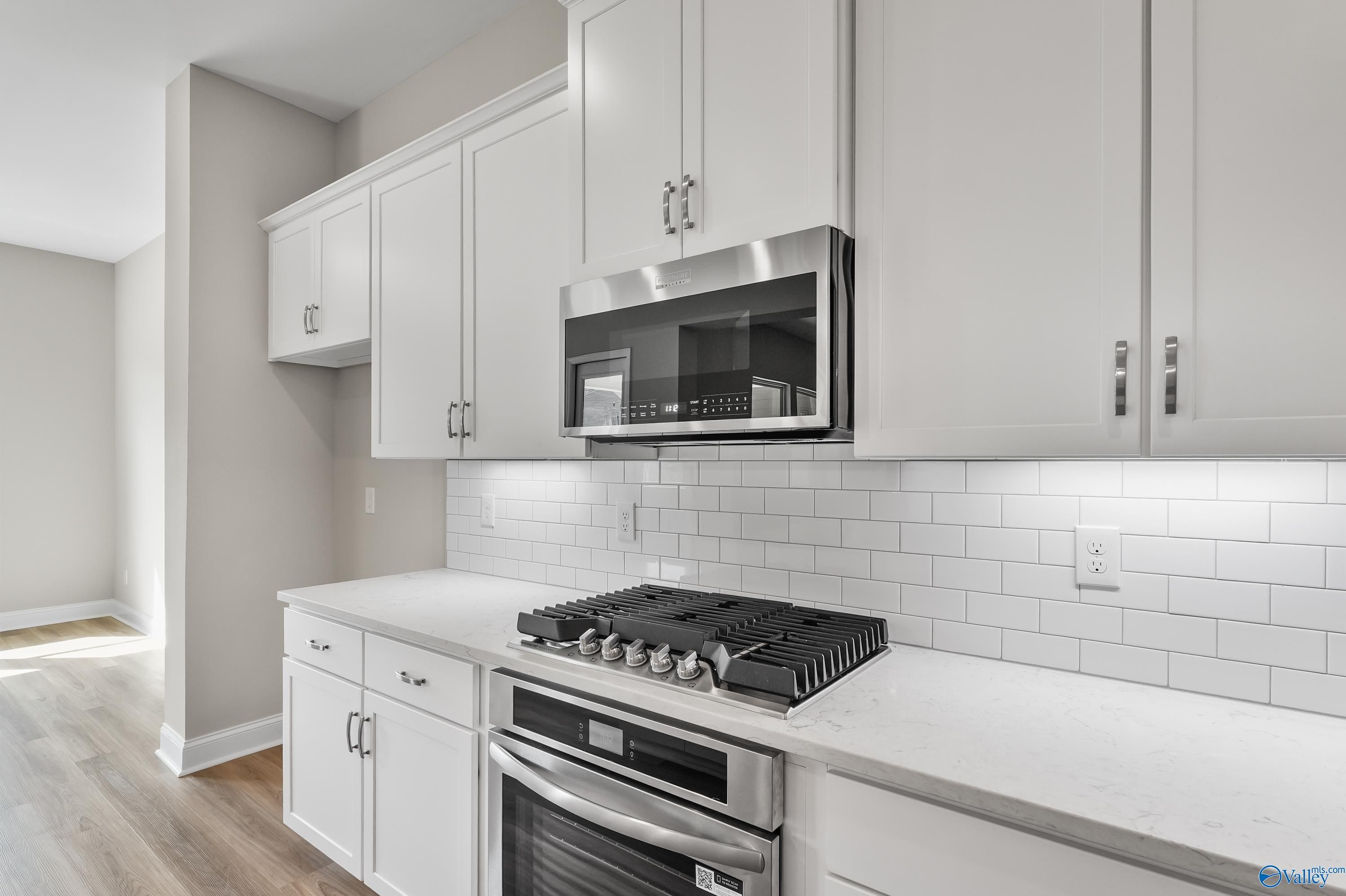 Modern kitchen with white shaker cabinets, stainless steel appliances, quartz counters in Evermore Homes The Haven, Owens Cross Roads, AL