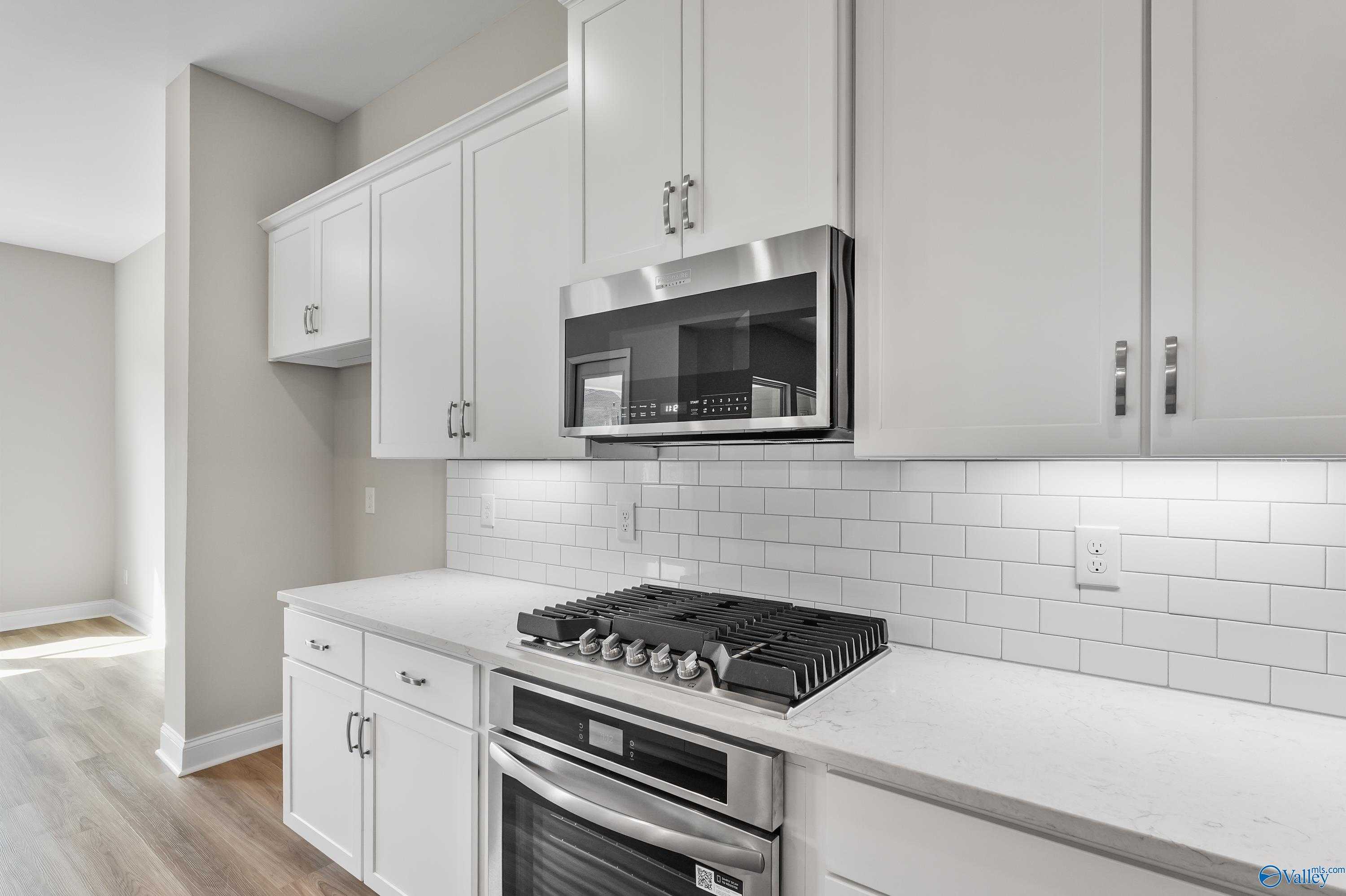 Modern kitchen with white shaker cabinets, stainless steel appliances, quartz counters in Evermore Homes The Haven, Owens Cross Roads, AL