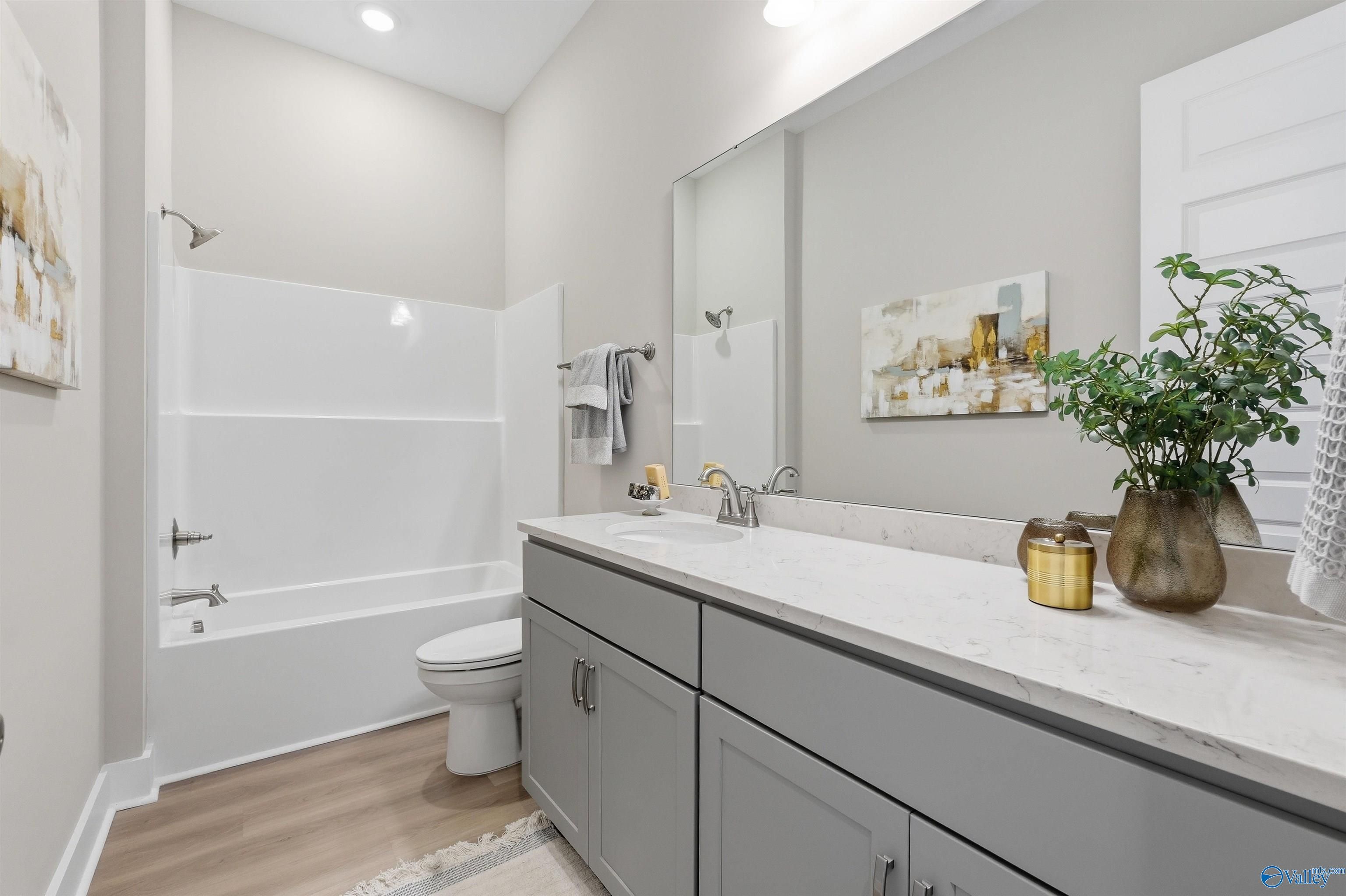 Modern guest bathroom with white tub-shower, gray vanity, quartz countertop in Evermore Homes The Oxford B, Owens Cross Roads, AL