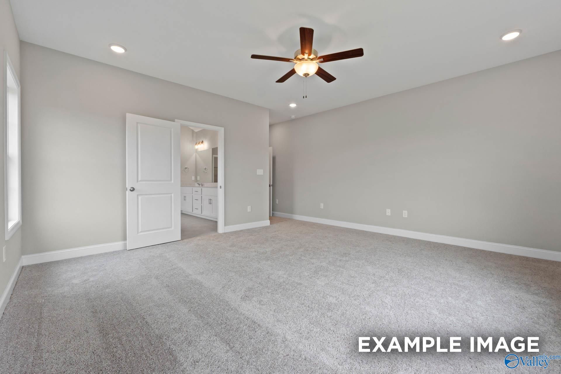 Spacious master bedroom with ceiling fan, carpet flooring, and en-suite bath in Davidson Homes The Finleigh, Harvest, Alabama