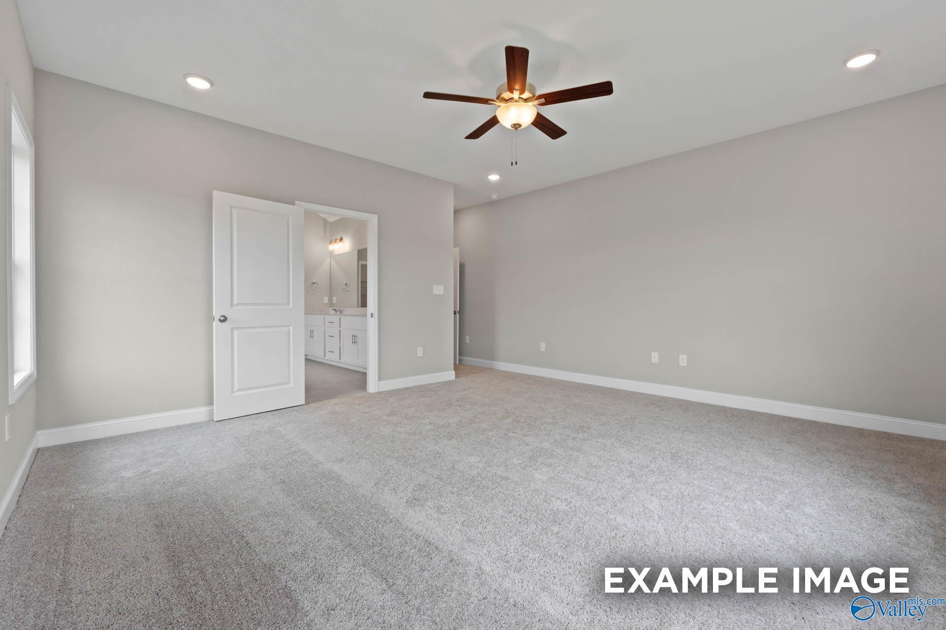 Spacious master bedroom with ceiling fan, carpet flooring, and en-suite bath in Davidson Homes The Finleigh, Harvest, Alabama