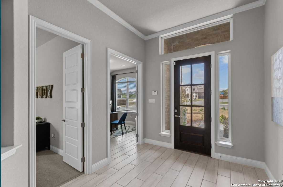 Welcoming entry foyer with dark wood front door, transom window, and gray walls in The Garner B 4-bedroom home, Ladera, San Antonio