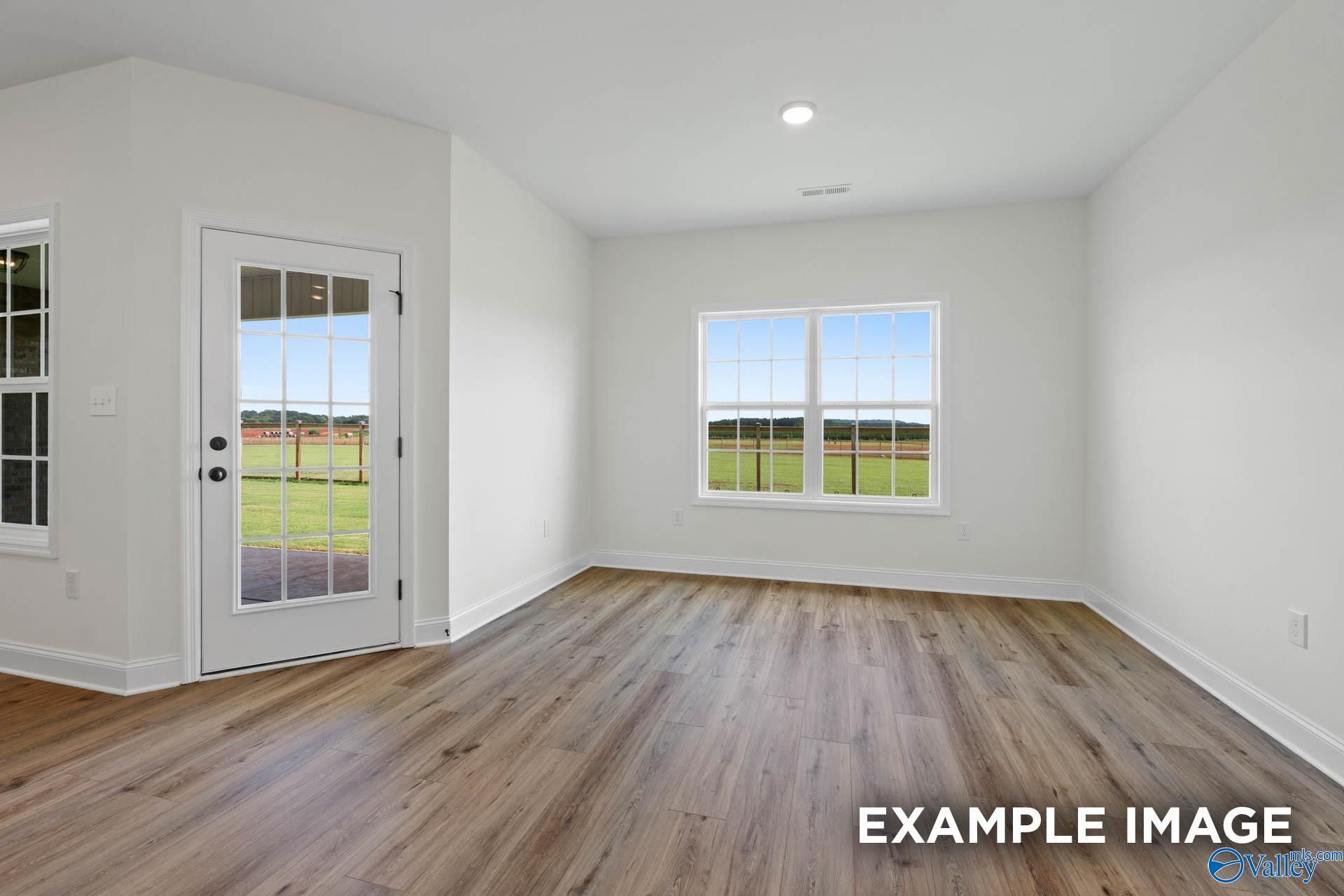 Bright, modern room with wood-look floors, large windows, and backyard access in The Rockford B home at Briercreek.