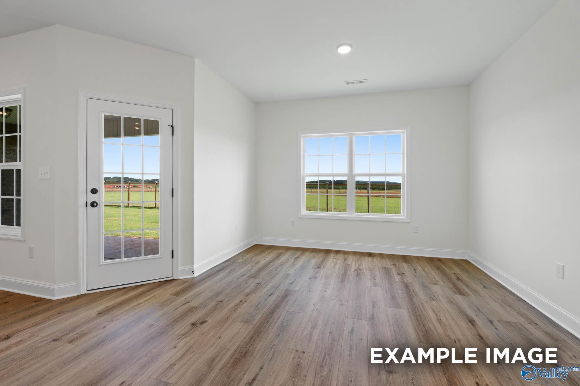 Bright, modern room with wood-look floors, large windows, and backyard access in The Rockford B home at Briercreek.