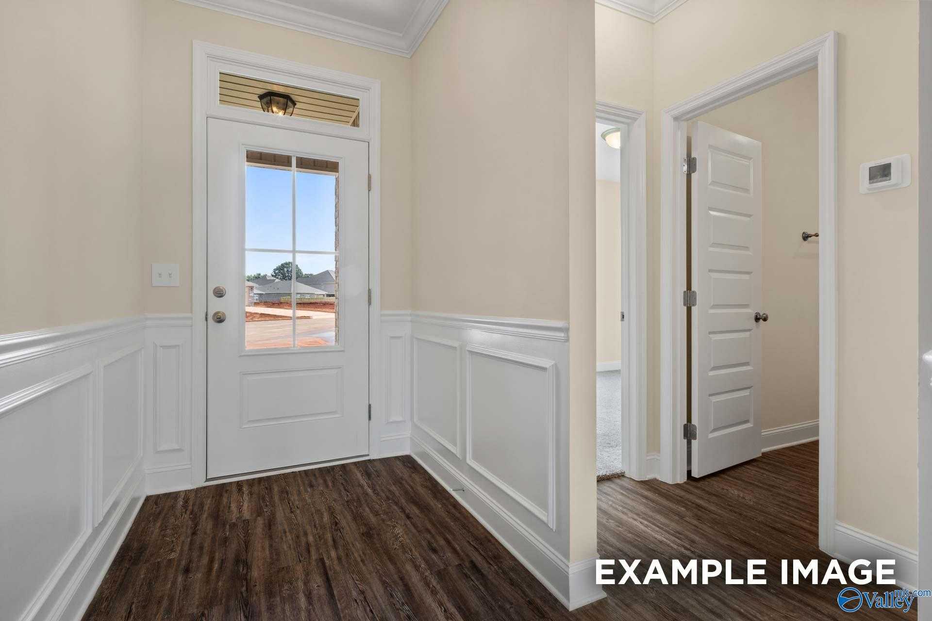 Elegant entryway with white glass-paneled door, wainscoting, wood floors in Davidson Homes The Asheville, Arab, Alabama