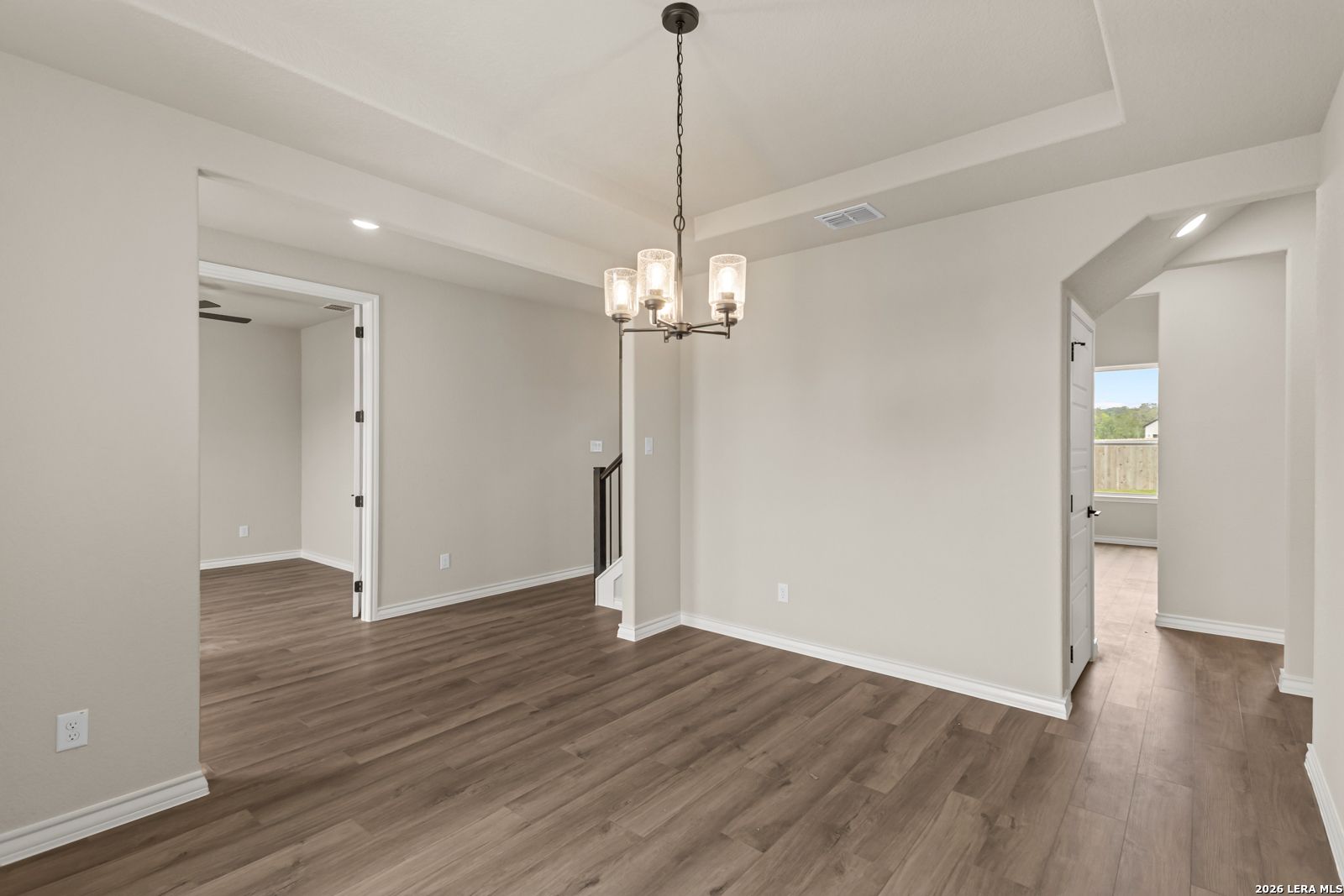 Elegant dining area with modern chandelier and wood-look flooring in The Danbury H home at The Reserve at Potranco Oaks.