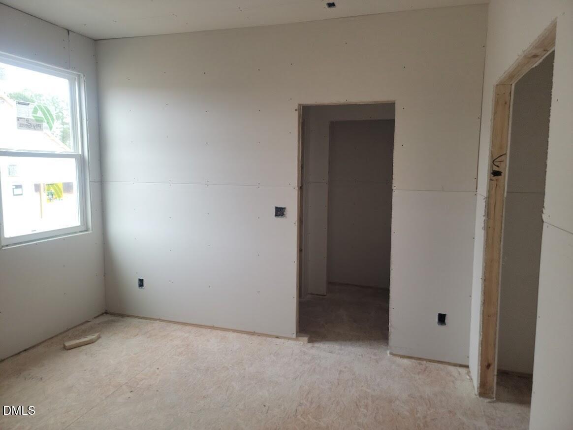 Spacious unfinished bedroom with drywall walls, large windows, and open doorways in new 5-bedroom Ashport G home, Angier, NC