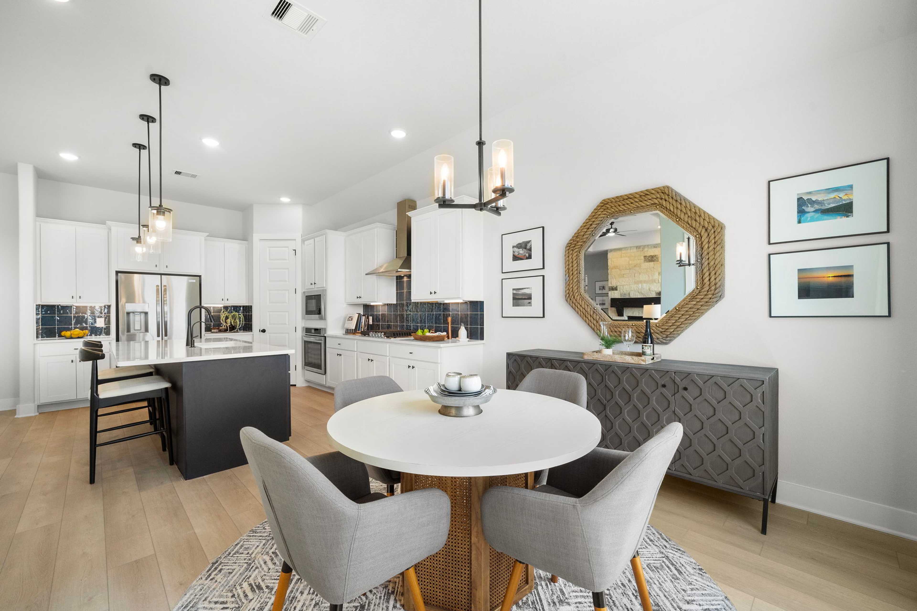 Modern open-concept kitchen dining area at Lago Mar in Texas City Texas by Davidson Homes featuring white cabinets black island and round table