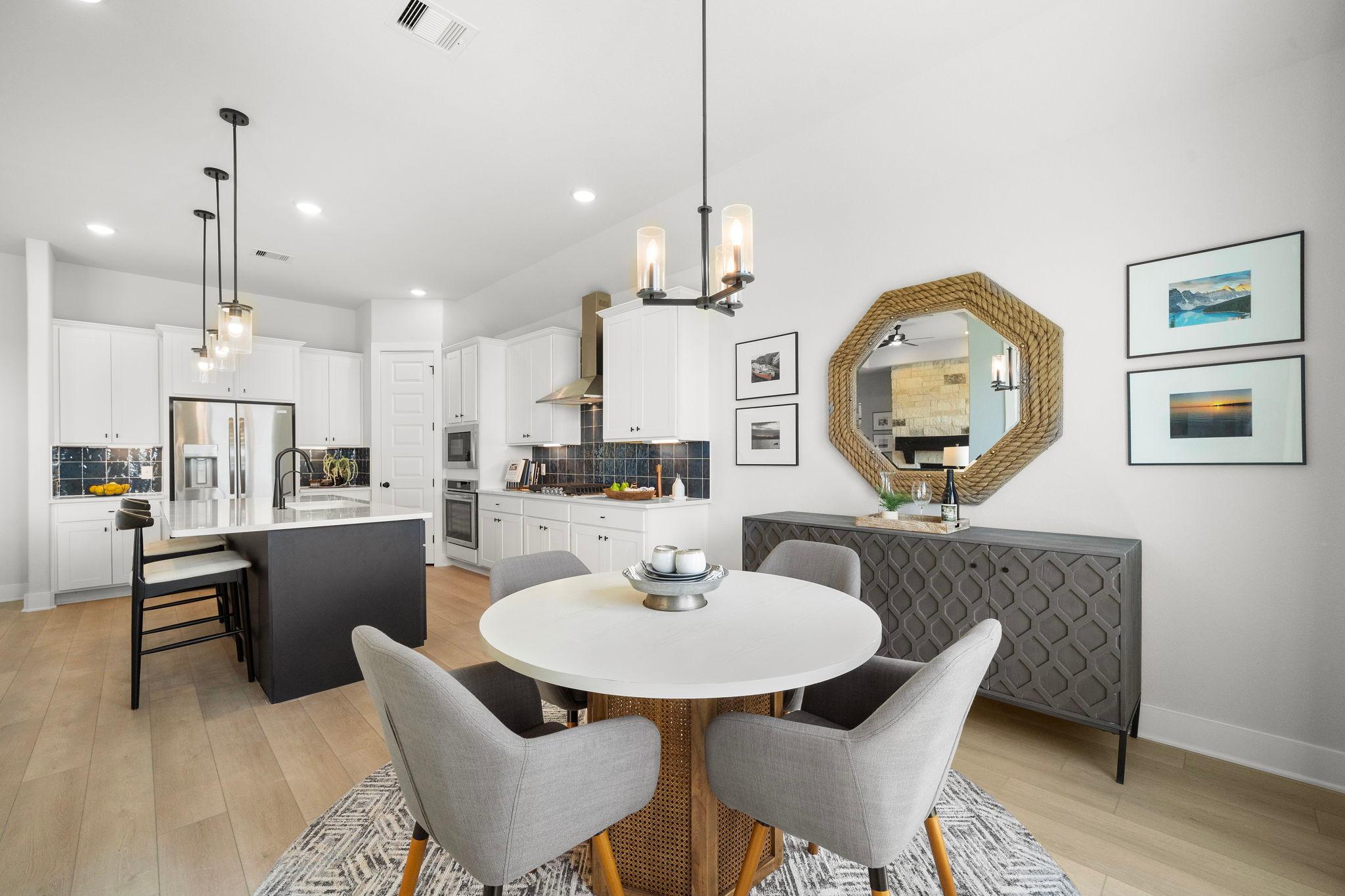 Modern open-concept kitchen dining area at Lago Mar in Texas City Texas by Davidson Homes featuring white cabinets black island and round table
