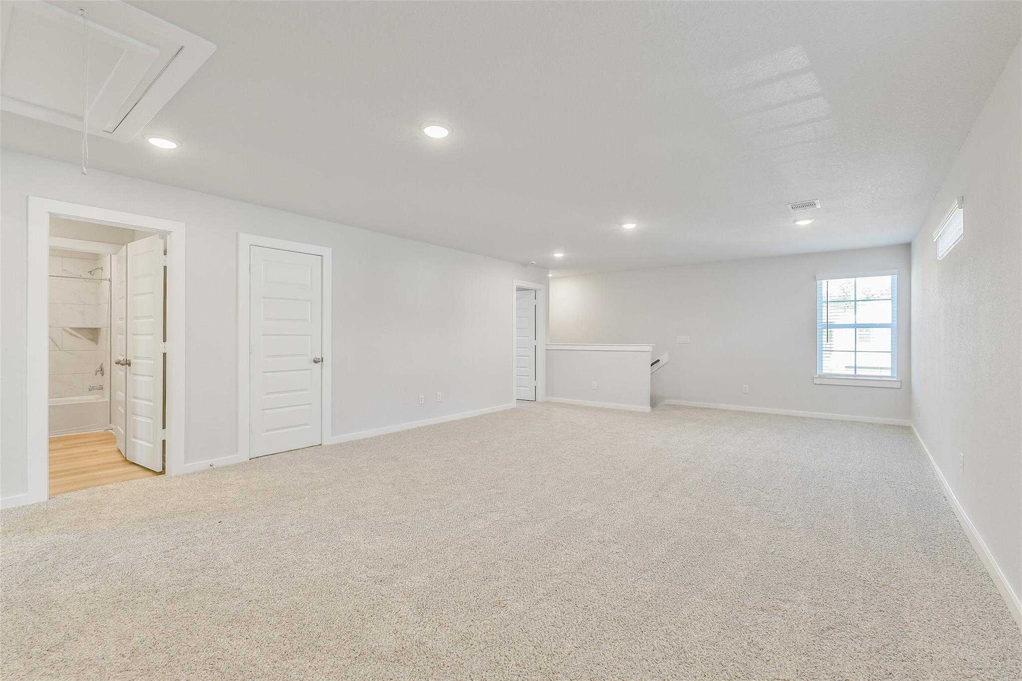 Spacious upstairs bonus room with bar counter, adjacent bathroom, and large window in 5-bedroom Davidson Homes The Rio Grande H, Magnolia, Texas
