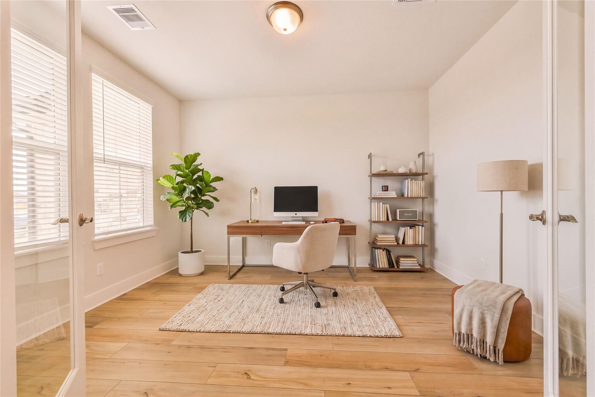 Bright modern home office with wooden desk, white leather chair, fiddle leaf plant, bookshelves in Davidson Homes The Victoria A, Lago Mar, Texas City