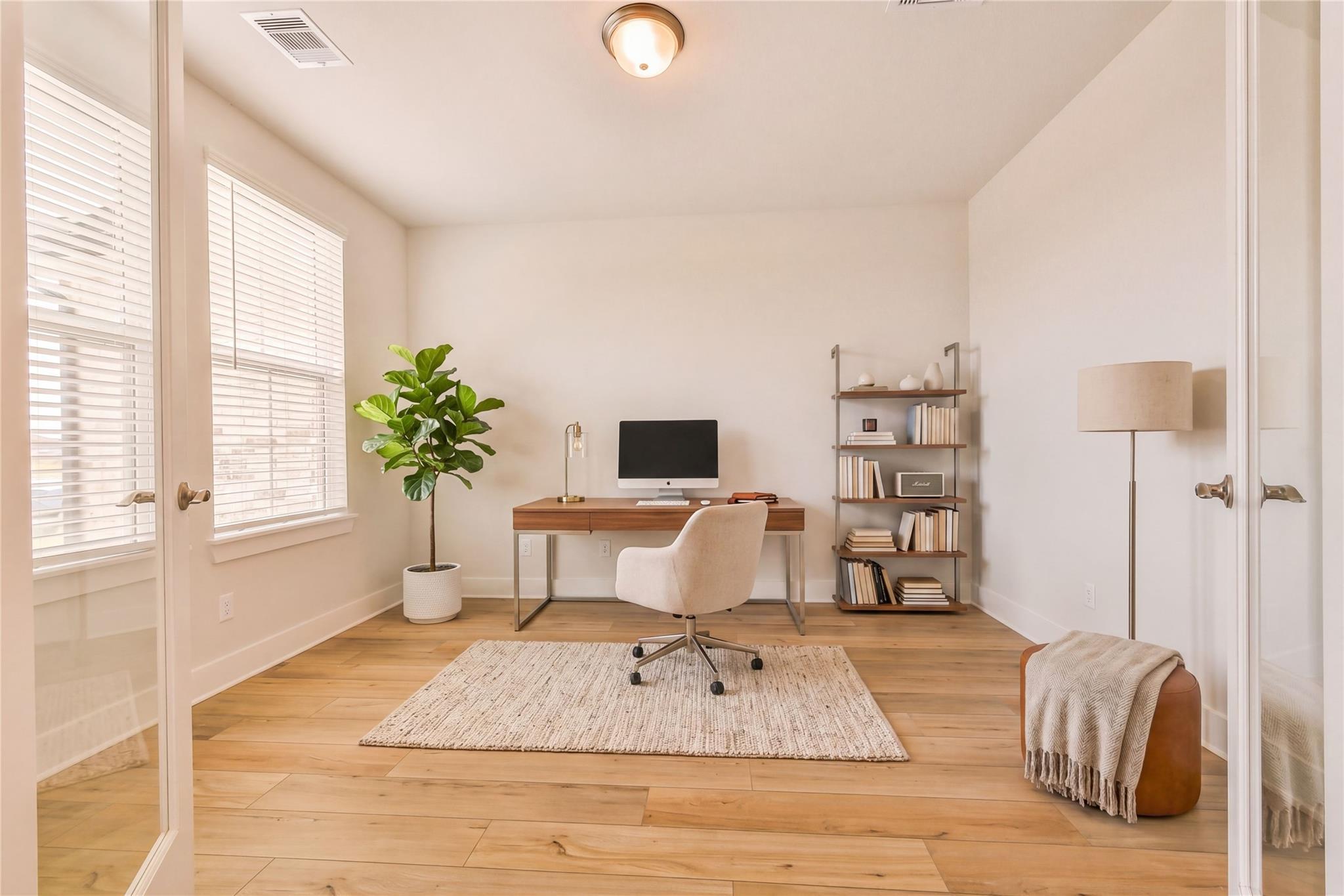 Bright modern home office with wooden desk, white leather chair, fiddle leaf plant, bookshelves in Davidson Homes The Victoria A, Lago Mar, Texas City