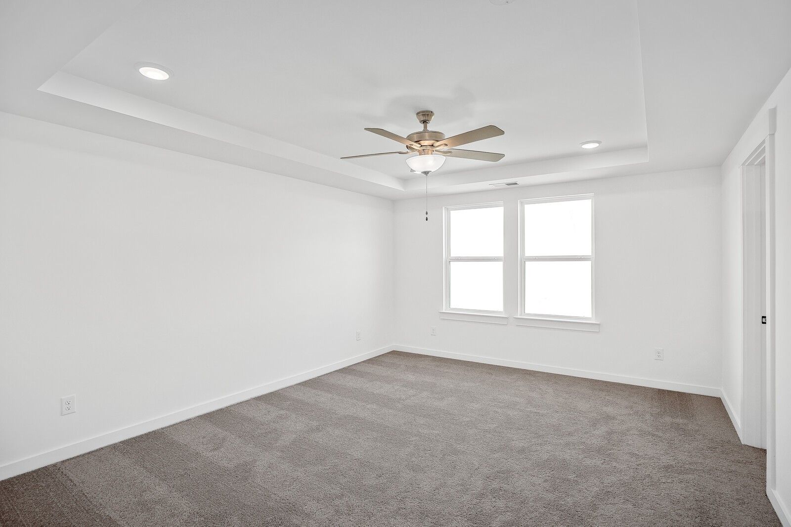 Bright empty bedroom with white walls, ceiling fan, large windows and carpet floor in Davidson Homes The Logan C, Gallatin TN