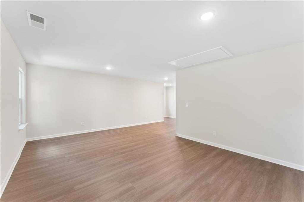 Empty living area with hardwood floors, beige walls, and recessed lighting in Davidson Homes The Ash B-Unfinished Basement, Riverwood, Dallas, GA