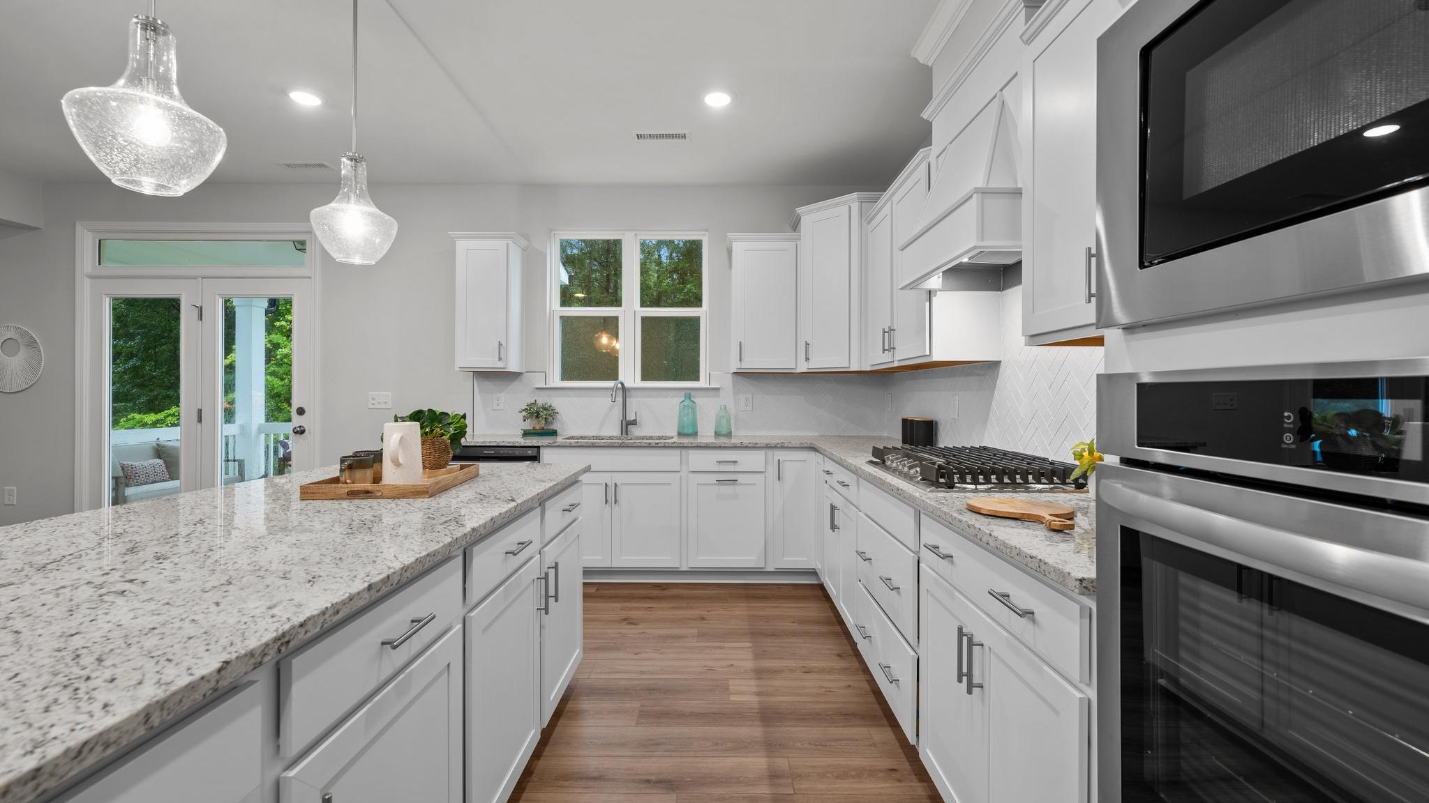 Spacious modern kitchen in Montrose Aberdeen NC with white shaker cabinets, quartz island, stainless appliances, pendant lights, French doors