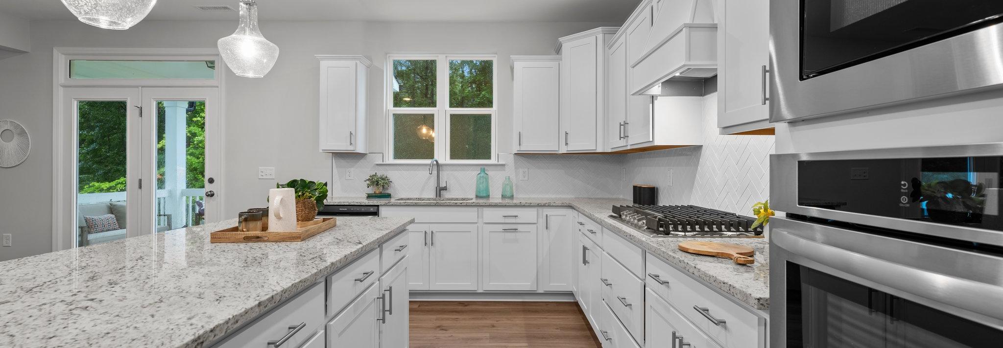 Spacious modern kitchen in Montrose Aberdeen NC with white shaker cabinets, quartz island, stainless appliances, pendant lights, French doors