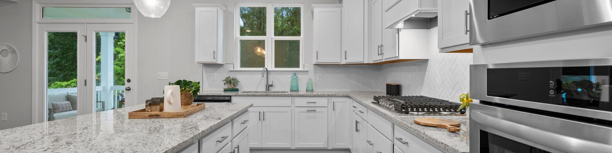 Spacious modern kitchen in Montrose Aberdeen NC with white shaker cabinets, quartz island, stainless appliances, pendant lights, French doors