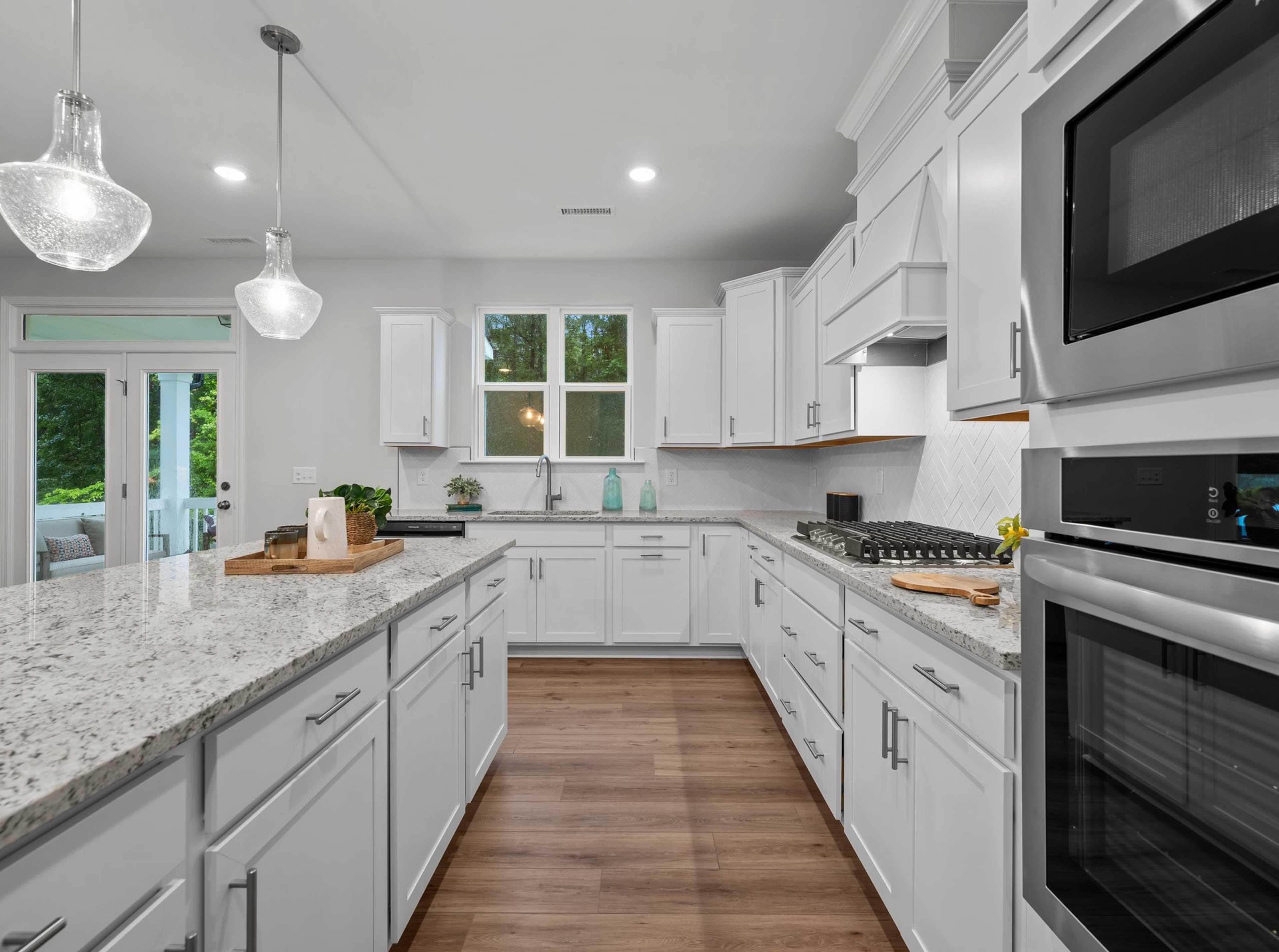 Spacious white kitchen with quartz island, stainless appliances, and French doors at Forestville Yard in Knightdale NC