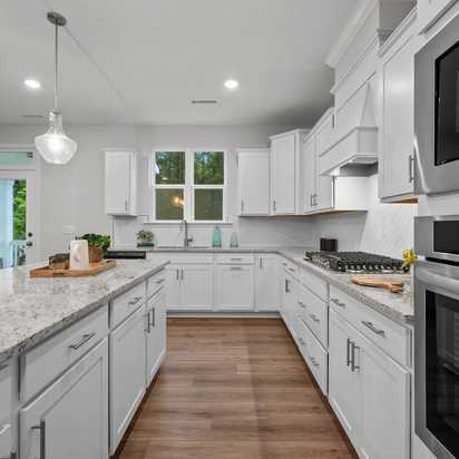 Spacious modern kitchen in Montrose Aberdeen NC with white shaker cabinets, quartz island, stainless appliances, pendant lights, French doors