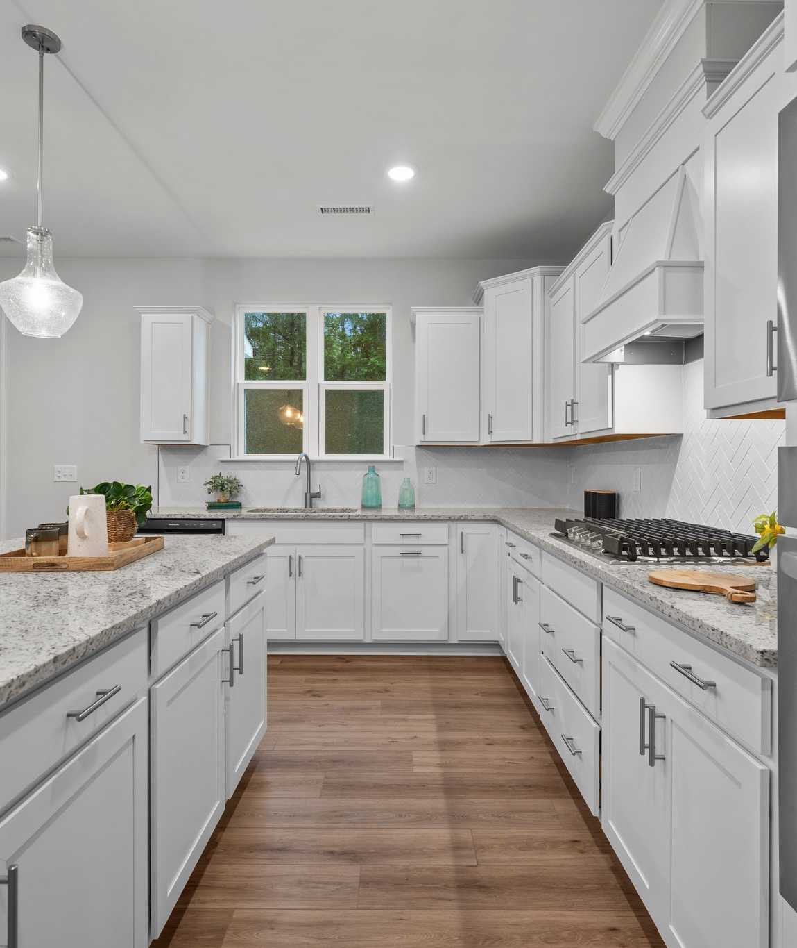 Spacious modern kitchen in Montrose Aberdeen NC with white shaker cabinets, quartz island, stainless appliances, pendant lights, French doors
