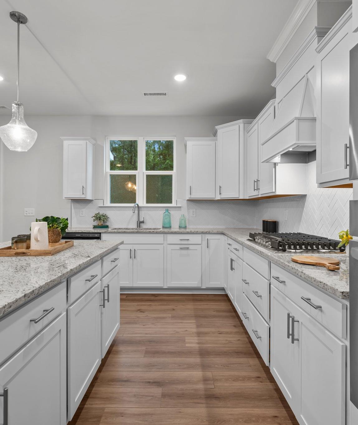 Spacious white kitchen with quartz island, stainless appliances, and French doors at Forestville Yard in Knightdale NC