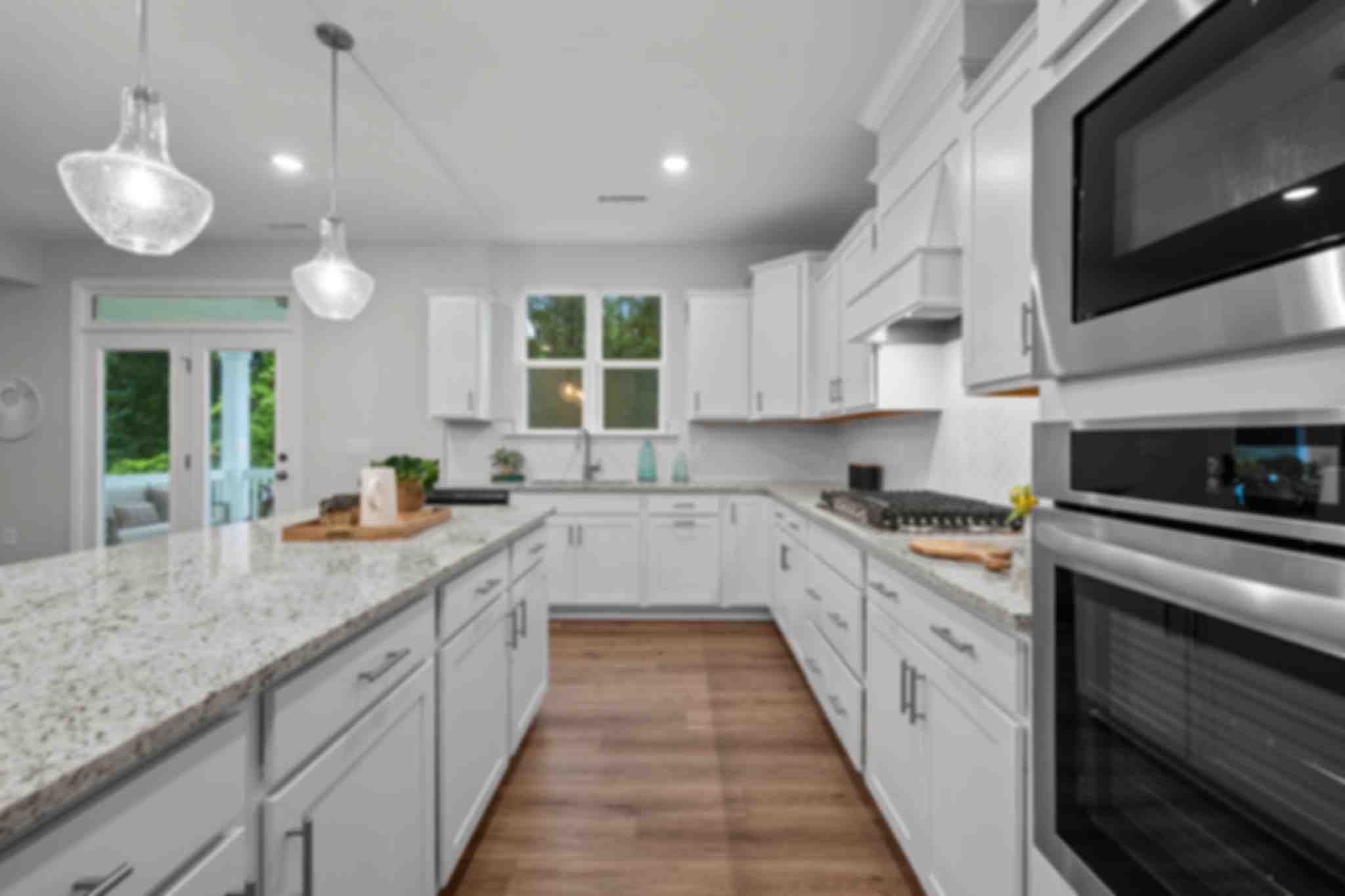 Spacious modern kitchen in Montrose Aberdeen NC with white shaker cabinets, quartz island, stainless appliances, pendant lights, French doors
