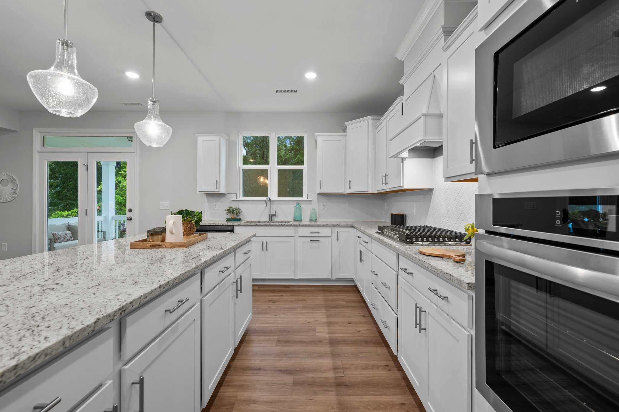 Spacious white kitchen with quartz island, stainless appliances, and French doors at Forestville Yard in Knightdale NC